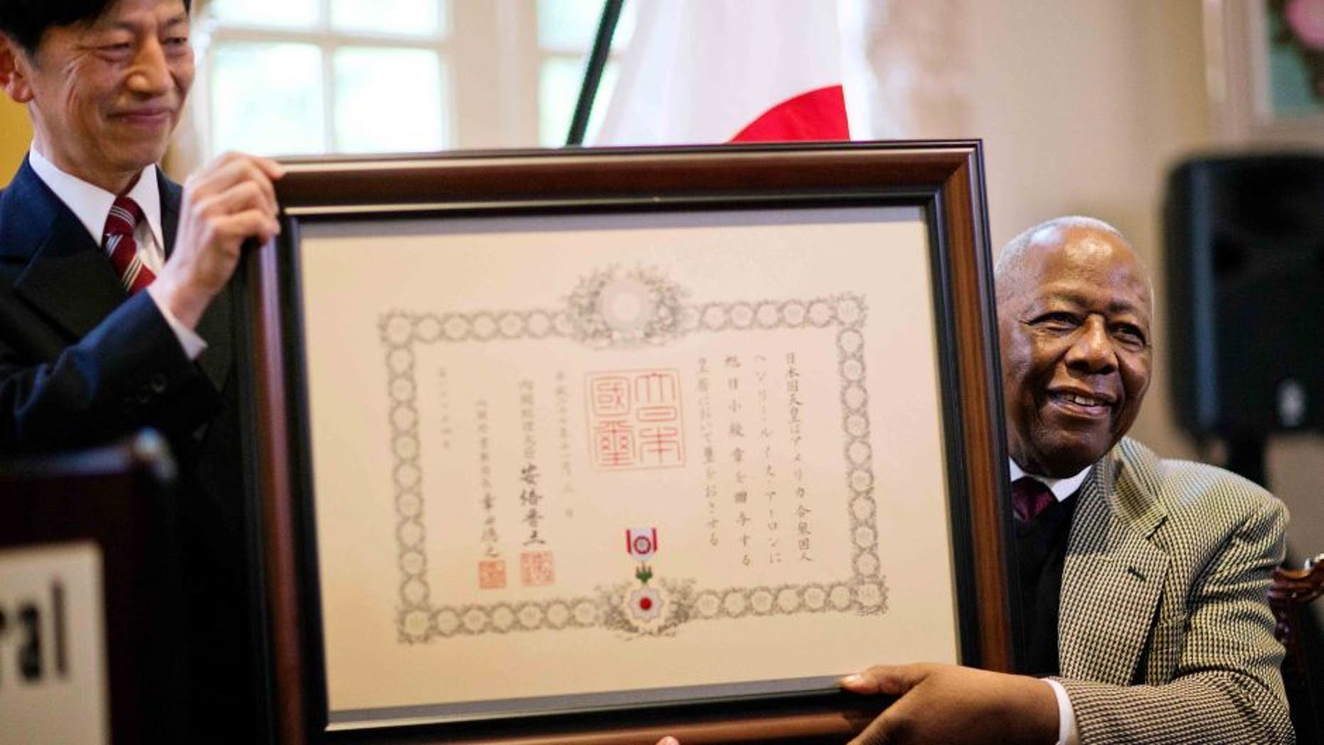 Hank Aaron, right, is presented with a framed certificate for the Order of the Rising Sun, Gold Rays with Rosette, by Takashi Shinozuka, left, Consul General of Japan in Atlanta, during a ceremony at the consul general's home, Thursday, Jan. 14, 2016, in Atlanta. Japan has honored the former home run king with one of its highest awards, bestowing the Order of the Rising Sun for bringing young people and countries together through baseball. (AP Photo/David Goldman)