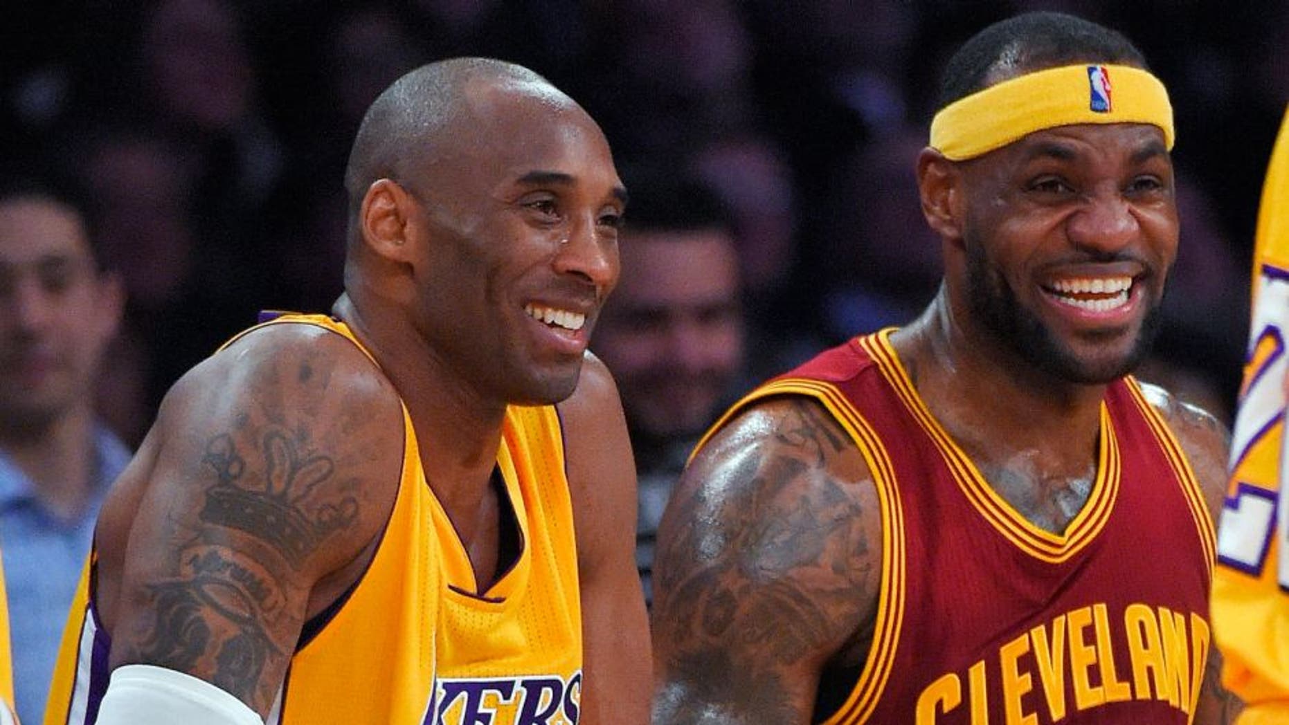 Los Angeles Lakers guard Kobe Bryant, left, and Cleveland Cavaliers forward LeBron James wait to come into the game during the first half of an NBA basketball game, Thursday, Jan. 15, 2015, in Los Angeles. (AP Photo/Mark J. Terrill)