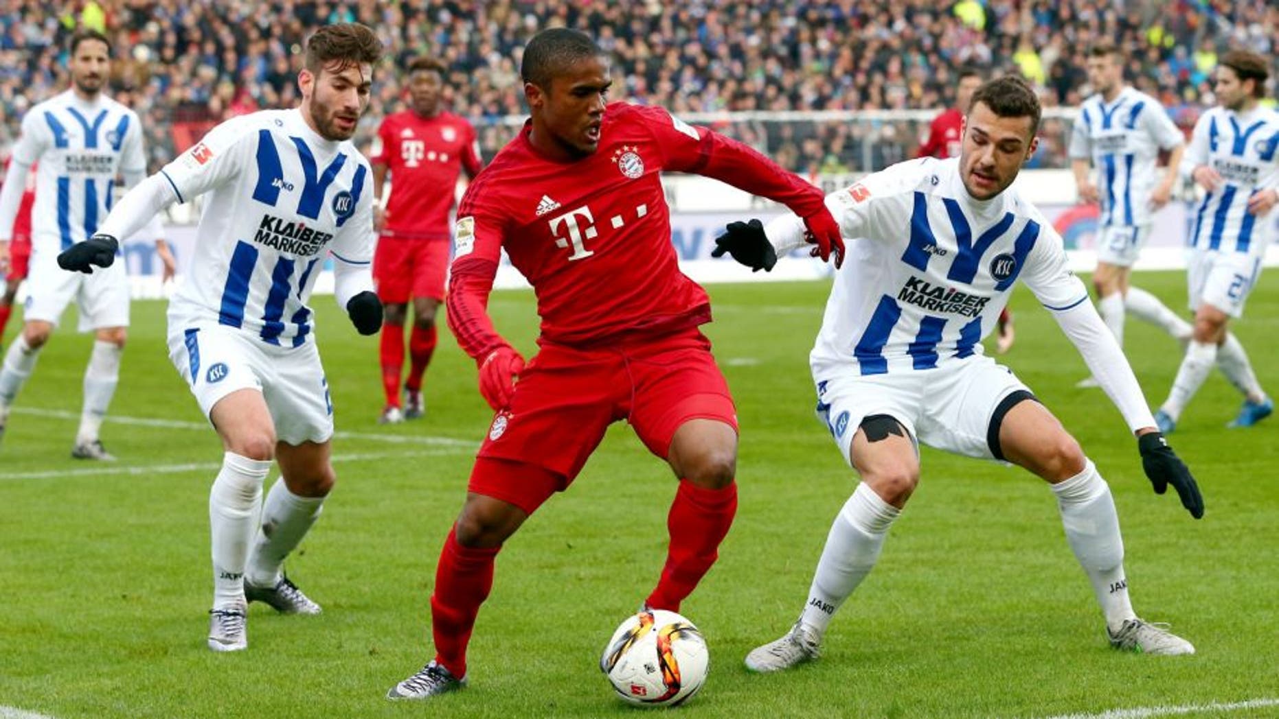 KARLSRUHE, GERMANY - JANUARY 16: Douglas Costa (C) of Muenchen is challenged by Enrico Valentini (L) and Manuel Gulde of Karlsruhe during a friendly match between Karlsruher SC and FC Bayern Muenchen at Wildpark Stadium on January 16, 2016 in Karlsruhe, Germany. (Photo by Alex Grimm/Bongarts/Getty Images)