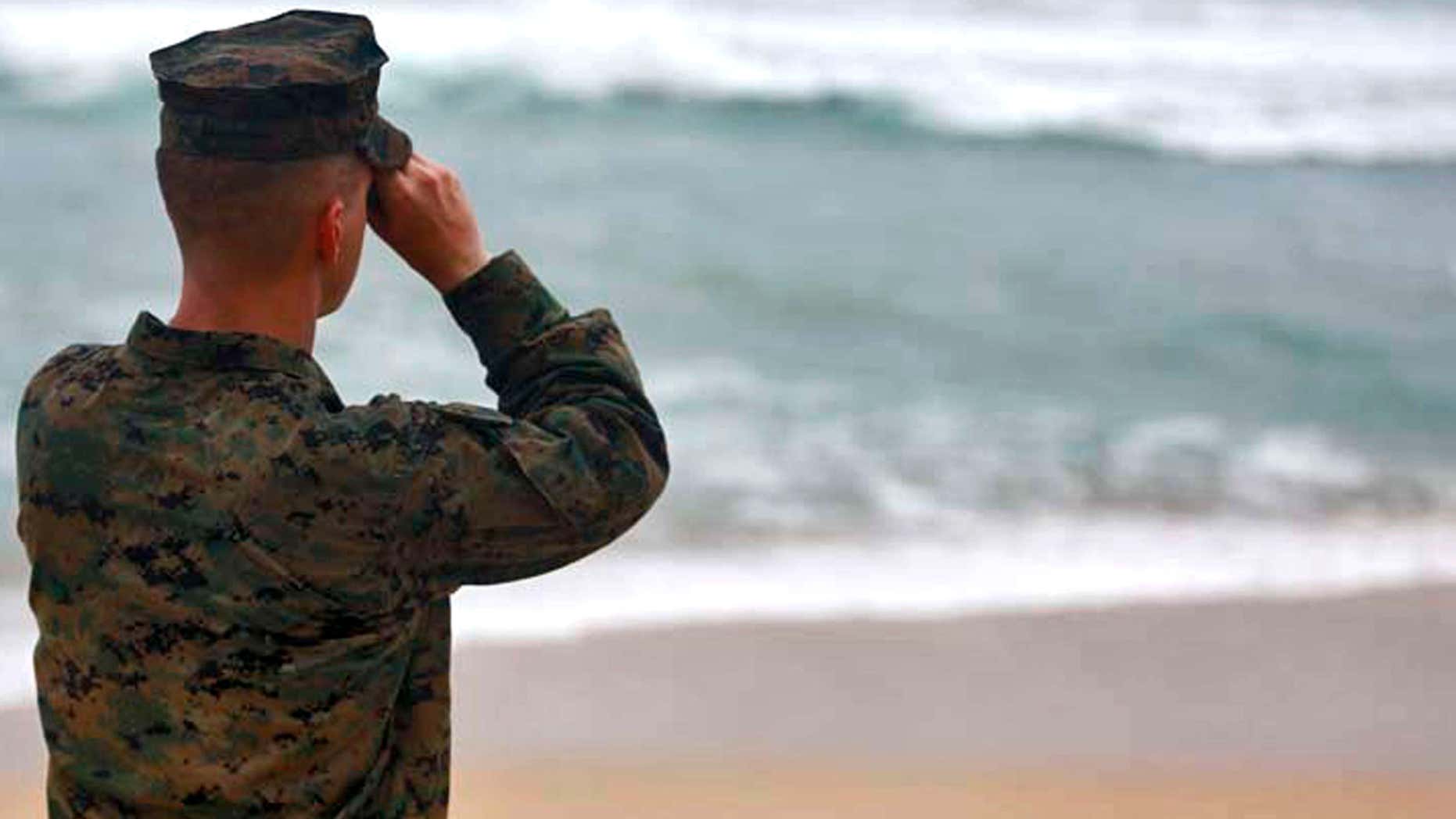 This Friday, Jan. 15, 2016 photo provided by the U.S. Marine Corps shows a Marine Officer attached to Marine Heavy Helicopter Squadron 463 uses binoculars to search for debris of a helicopter mishap in Haliewa Beach Park, Hawaii.