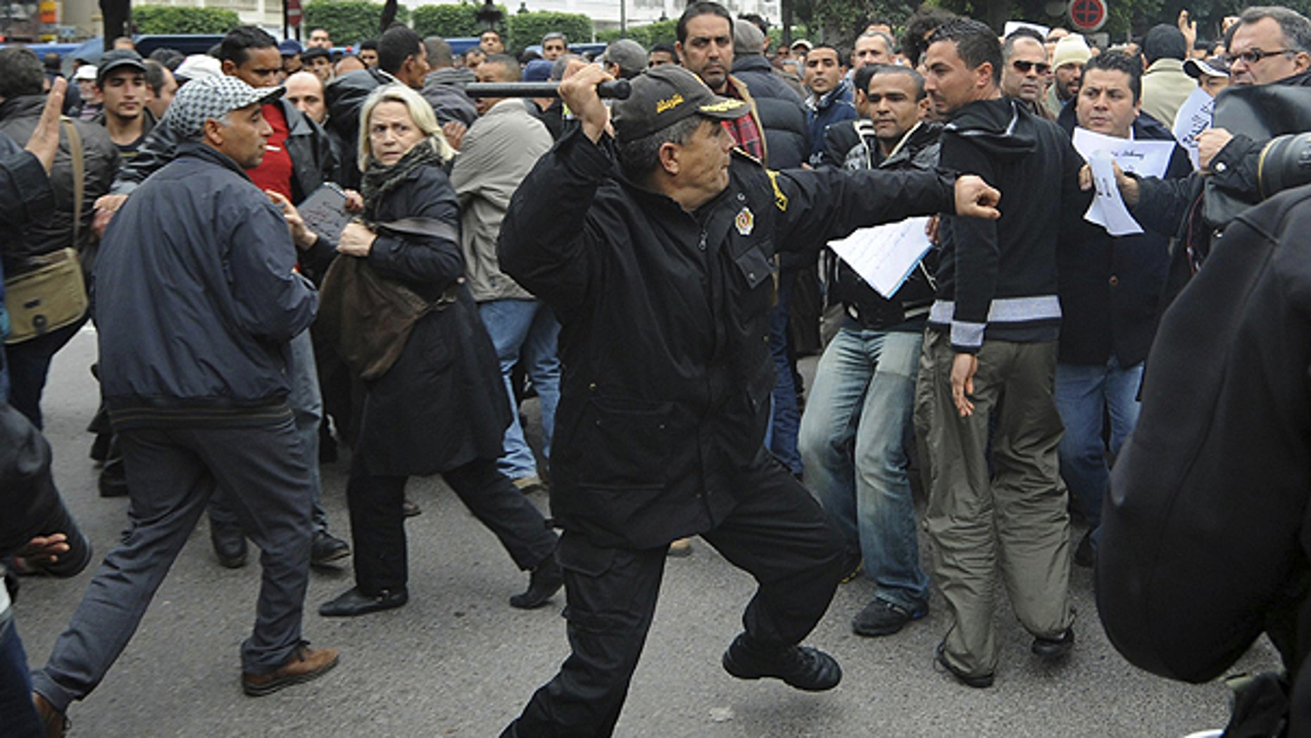 Jan. 18: A police officer faces protestors during a demonstration against the Constitutional Democratic Rally, RCD, party of Ben Ali in the center of Tunis.