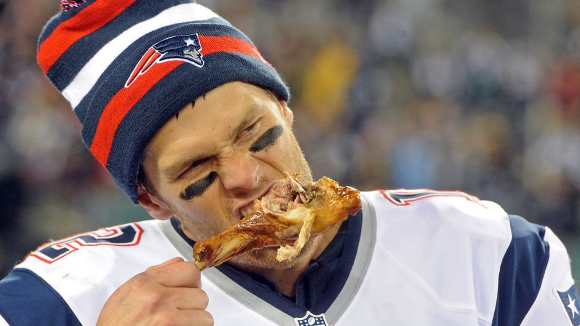 Nov 22, 2012; East Rutherford, NJ, USA; New England Patriots quarterback Tom Brady (12) takes a bite of turkey drumstick after the game against the New York Jets on Thanksgiving at Metlife Stadium. The Patriots won the game 49-19. Mandatory Credit: Joe Camporeale-USA TODAY Sports