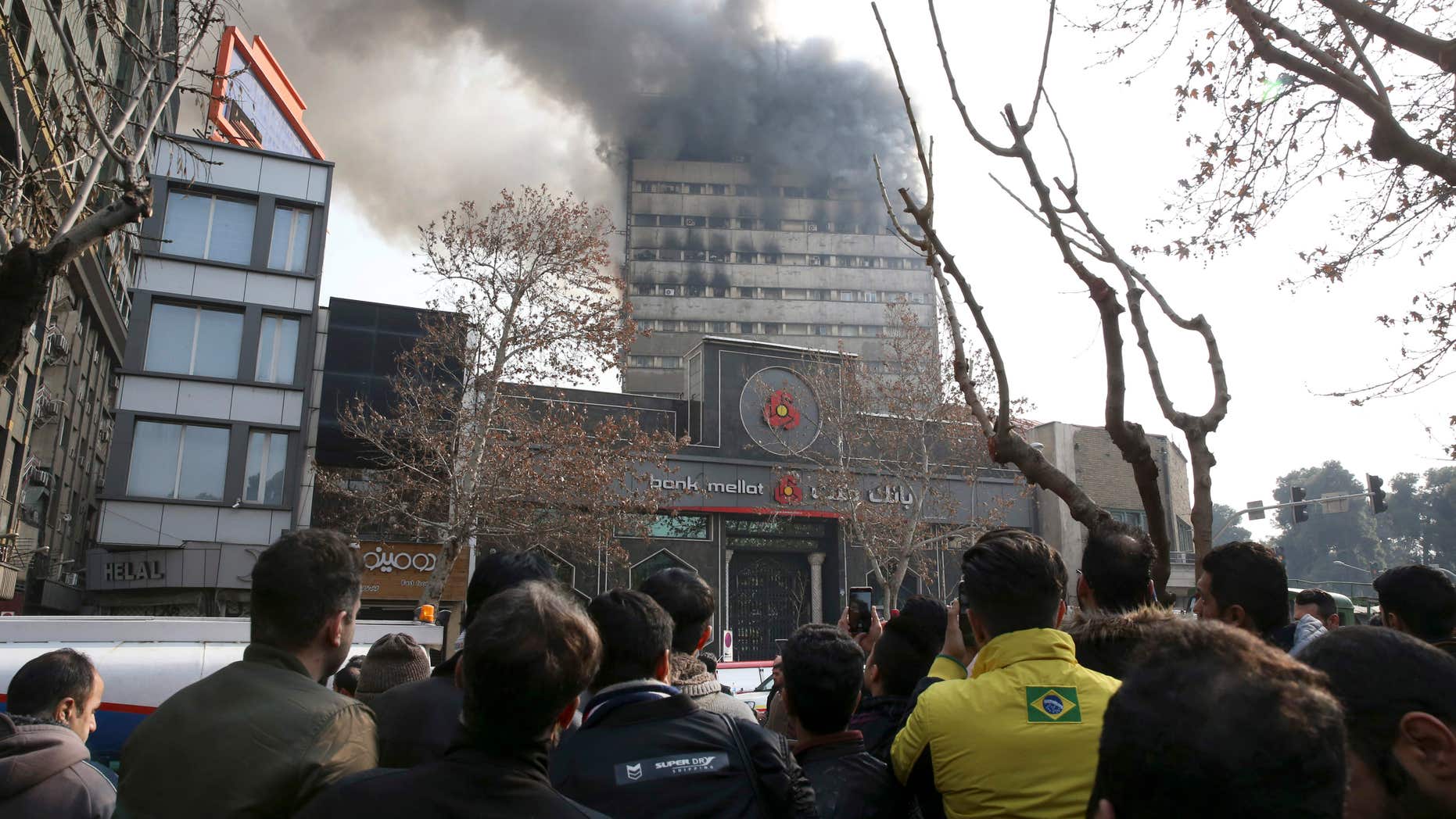Jan. 19, 2017: Iranians watch the Plasco building where smoke rises from its windows in central Tehran, Iran.