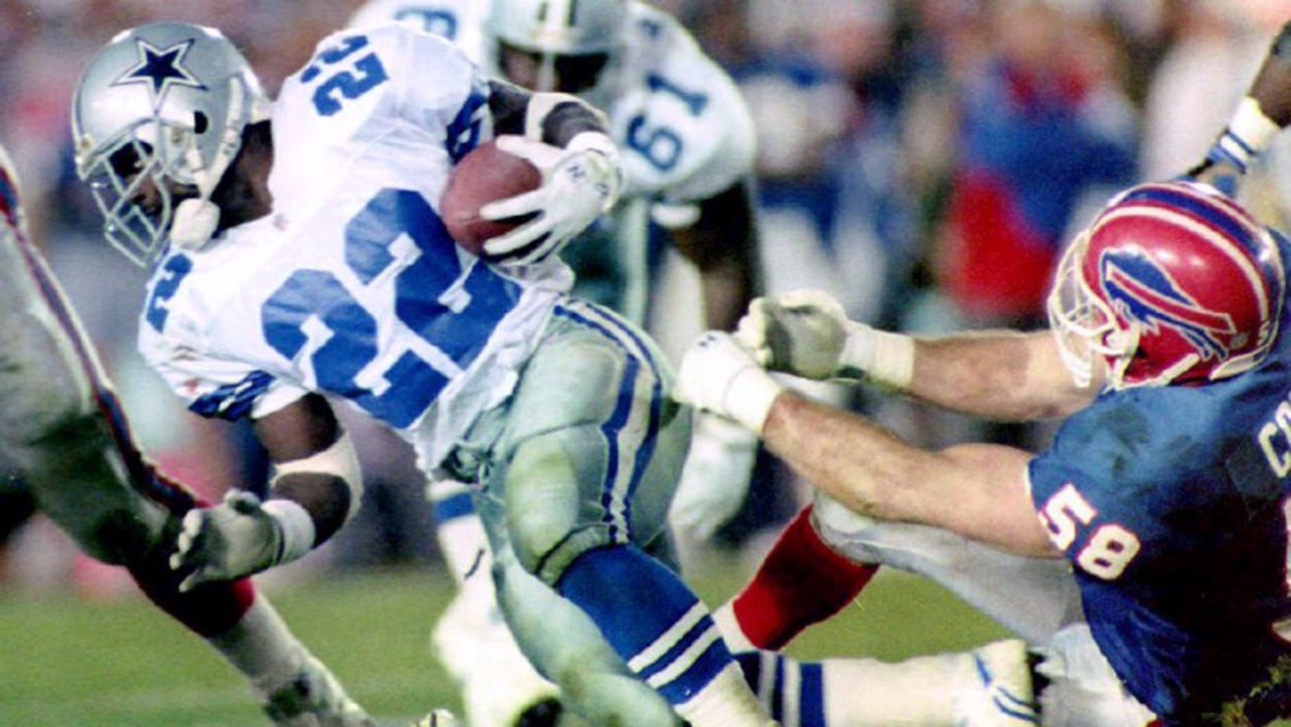 PASADENA, : Dallas Cowboys running back Emmitt Smith (L) breaks a tackle by Buffalo Bills linebacker Shane Conlan (R) 31 January, 1993 during fourth quarter action in Super Bowl XXVII in Pasadena, CA. Smith ran for 108 yards in 22 carries. The Cowboys won the game 52-17. (Photo credit should read TIM CLARY/AFP/Getty Images)