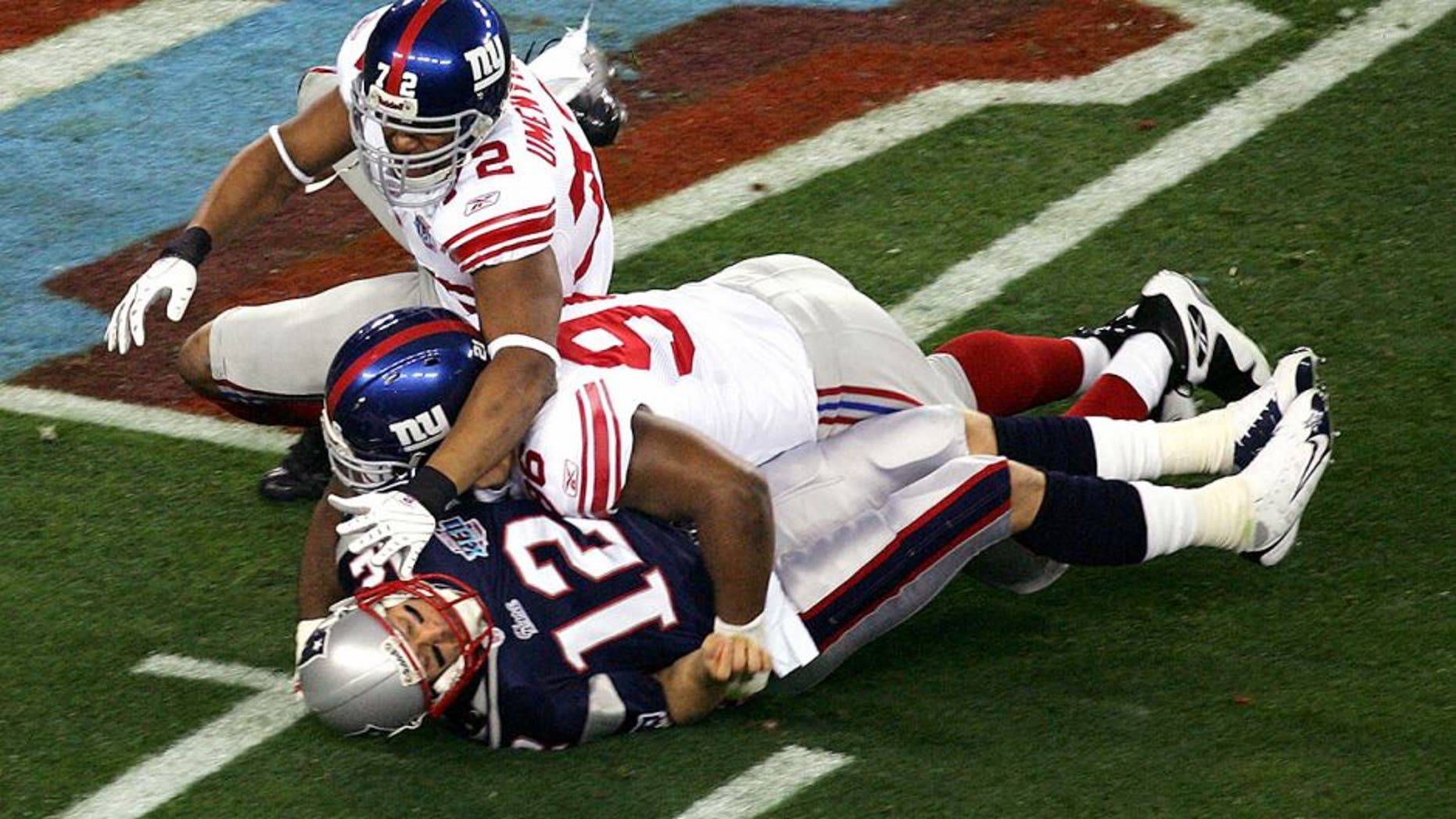GLENDALE, AZ - FEBRUARY 03: Quarterback Tom Brady #12 of the New England Patriots is hit as he throws by defensive tackle Barry Cofield #96 and Osi Umenyiora #72 of the New York Giants in the first half during Super Bowl XLII on February 3, 2008 at the University of Phoenix Stadium in Glendale, Arizona. (Photo by Jim McIsaac/Getty Images)