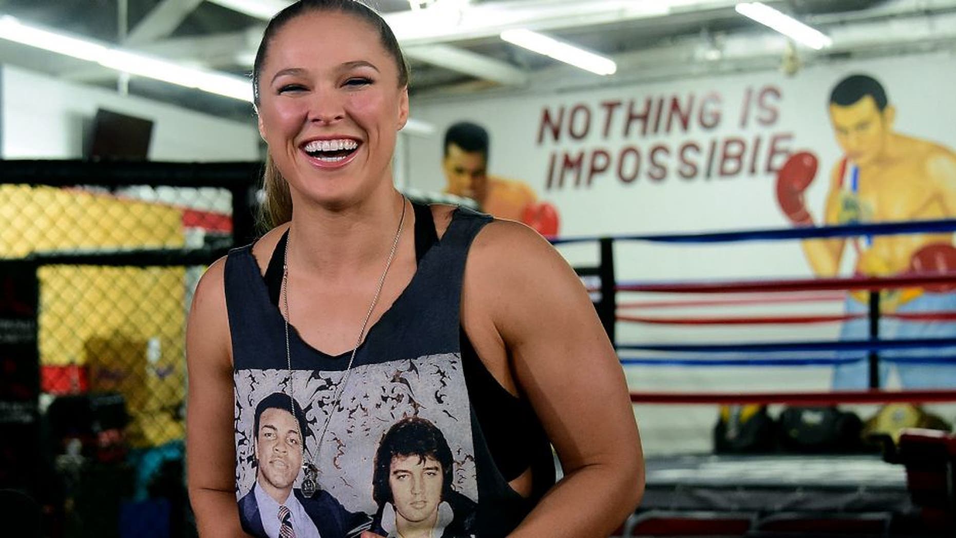 Mixed Martial Arts (MMA) fighter Ronda Rousey, wearing a shirt with portraits of former heavyweight boxing champion Muhammad Ali (L) and the late US singer Elvis Presley (R), responds to questions during media day in Glendale, California on October 27, 2015 ahead of her November 14 fight in Melbourne, Australia against Holly Holm. AFP PHOTO / FREDERIC J. BROWN (Photo credit should read FREDERIC J. BROWN/AFP/Getty Images)