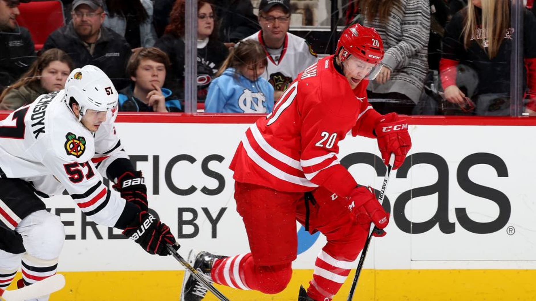 RALEIGH, NC - JANUARY 26: Riley Nash #20 of the Carolina Hurricanes gets out on a breakaway as Trevor van Riemsdyk #57 of the Chicago Blackhawks steals the puck during an NHL game at PNC Arena on January 26, 2016 in Raleigh, North Carolina. (Photo by Gregg Forwerck/NHLI via Getty Images)
