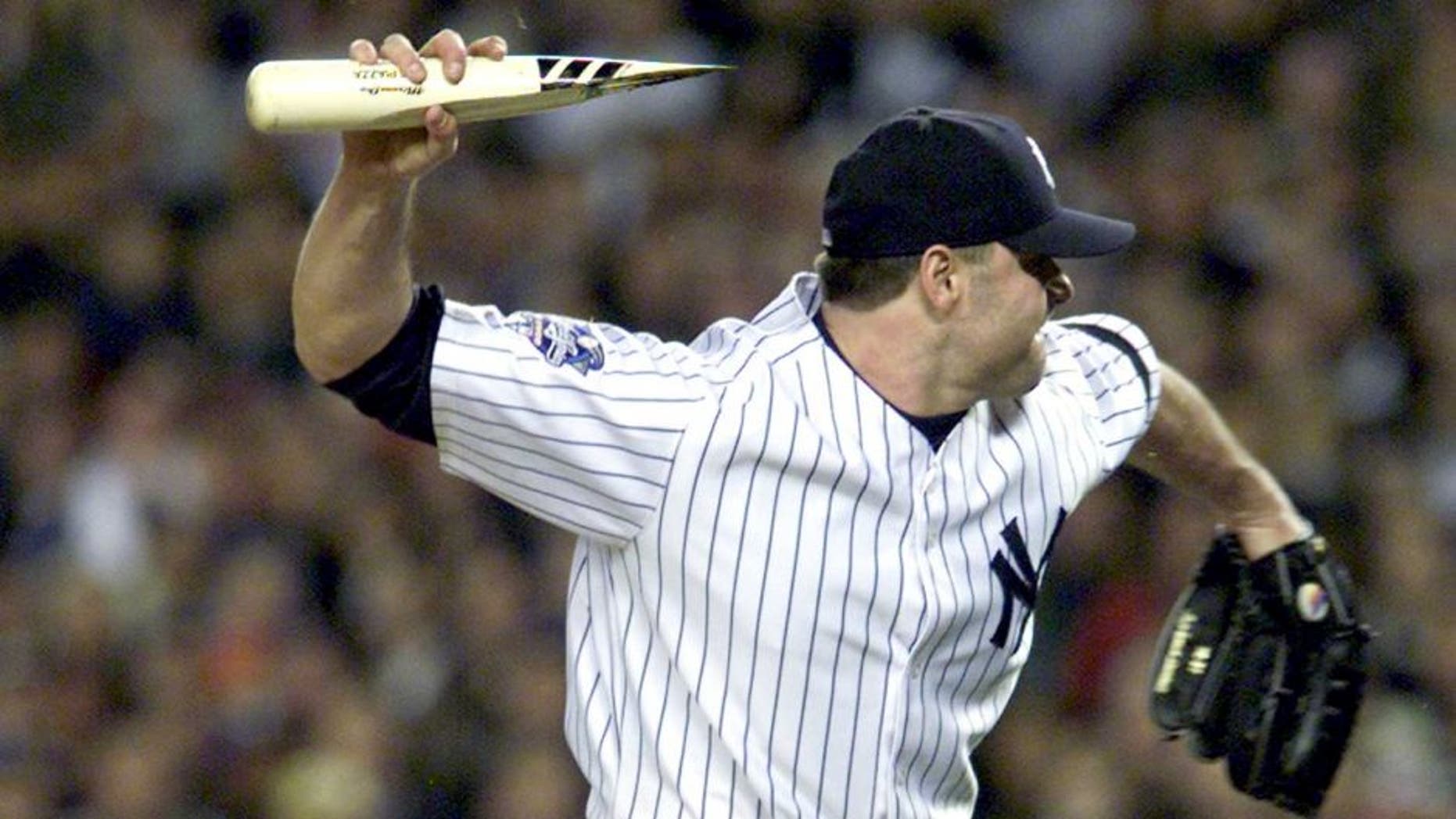 NEW YORK, UNITED STATES: New York Yankees pitcher Roger Clemens throws the broken bat of Mike Piazza of the New York Mets as Piazza runs to first base during the first inning of the Second Game of the World Series in New York City 22 October, 2000. The incident lead to a dugout emptying confrontation between the two teams. Piazza'a bat broke after hitting the ball and a piece of it flew in the direction of the mound. AFP PHOTO AFP PHOTO/Matt CAMPBELL (Photo credit should read MATT CAMPBELL/AFP/Getty Images)