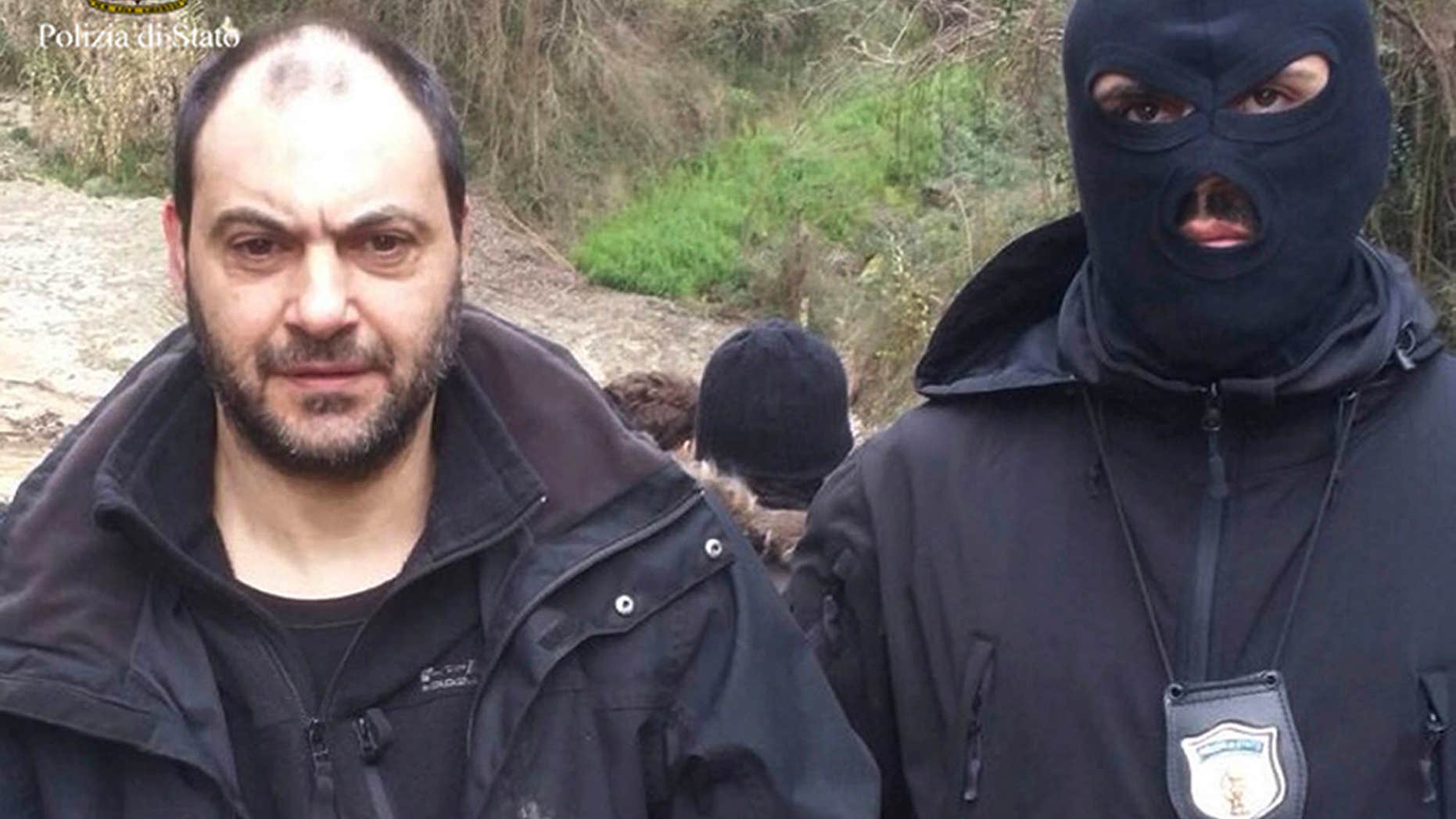 In this photo released by the Italian Police Friday, Jan. 29, 2016, Giuseppe Ferraro is taken into custody after he was arrested in a bunker.