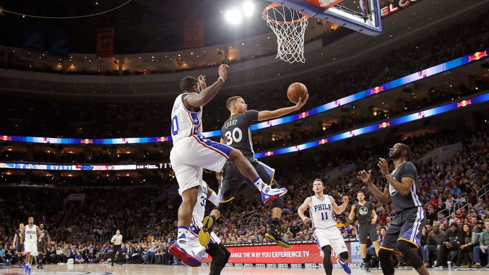 Golden State Warriors' Stephen Curry (30) goes up for a shot past Philadelphia 76ers' Isaiah Canaan (0) during the first half of an NBA basketball game Saturday, Jan. 30, 2016, in Philadelphia. (AP Photo/Matt Slocum)