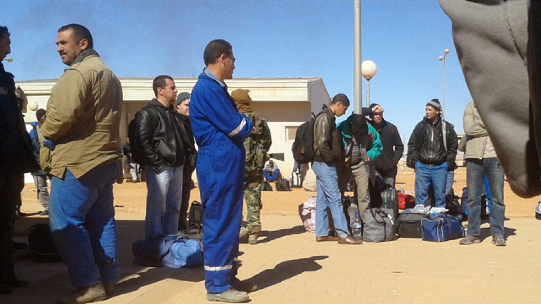Jan. 16, 2013: In this photo secretly taken by a hostage, an Islamic militant, rear center, in camouflage uniform, stands among Algerian employees who were forced to leave their houses with their belongings at the Ain Amenas natural gas complex in Ain Amenas, Algeria.