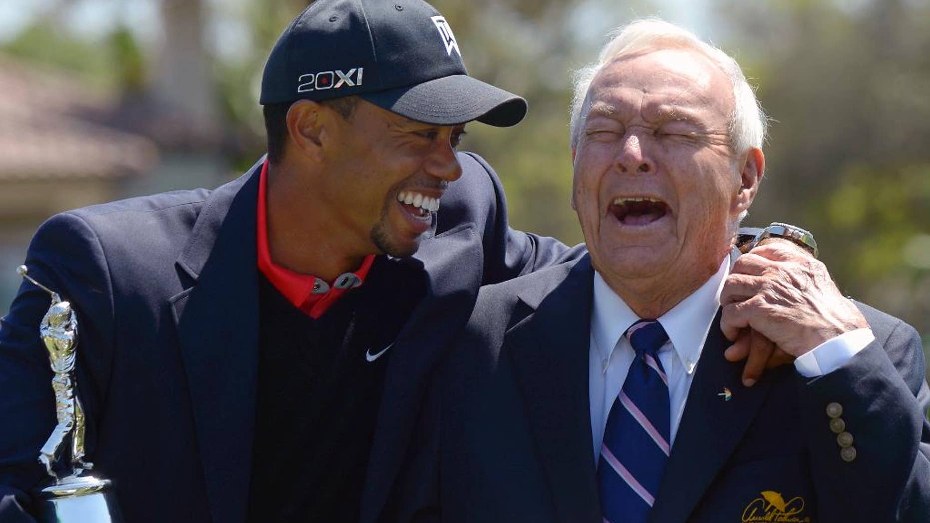 FILE - In this Monday, March 25, 2013 file photo, Tiger Woods, left, and Arnold Palmer share a laugh during the trophy presentation after Woods won the Arnold Palmer Invitational golf tournament in Orlando, Fla. Tiger Woods won't be at the Arnold Palmer Invitational next week and still doesn't know when he will play again. Woods announced on his website Thursday night, March 9, 2017 that ongoing rest and rehabilitation on his back will keep him away from Bay Hill and the tournament he has won a record eight times. (AP Photo/Phelan M. Ebenhack, File)
