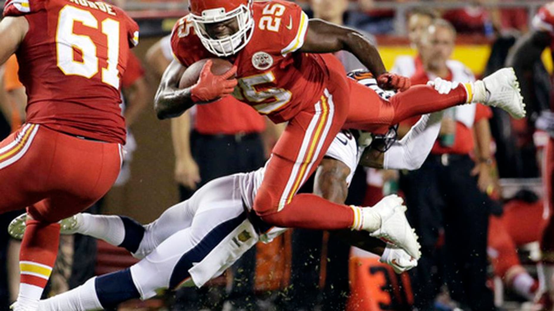 FILE - In this Sept. 17, 2015, file photo, Kansas City Chiefs running back Jamaal Charles (25) is tackled by Denver Broncos cornerback Chris Harris Jr., rear, during the second half of an NFL football game in Kansas City, Mo. Adrian Peterson and Jamaal Charles, both stalwarts for their previous clubs and with All-Pro credentials, are out there. But how many 30-plus running backs get long-term deals, even proven ones such as these? And both will want big bucks. (AP Photo/Charlie Riedel, File)