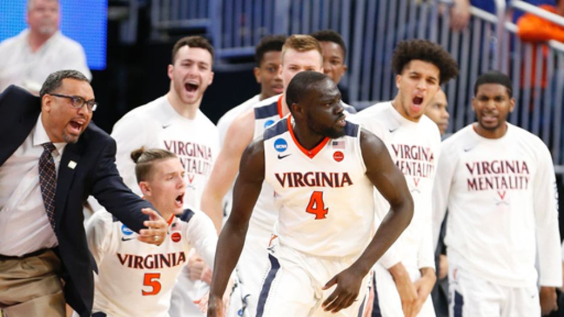 Players and coaches come off the bench as Virginia guard Marial Shayok (4) scores against UNC Wilmington during the second half of a first-round men's college basketball game in the NCAA Tournament, Thursday, March 16, 2017, in Orlando, Fla. Virginia defeated UNC Wilmington 76-71. (AP Photo/Wilfredo Lee)