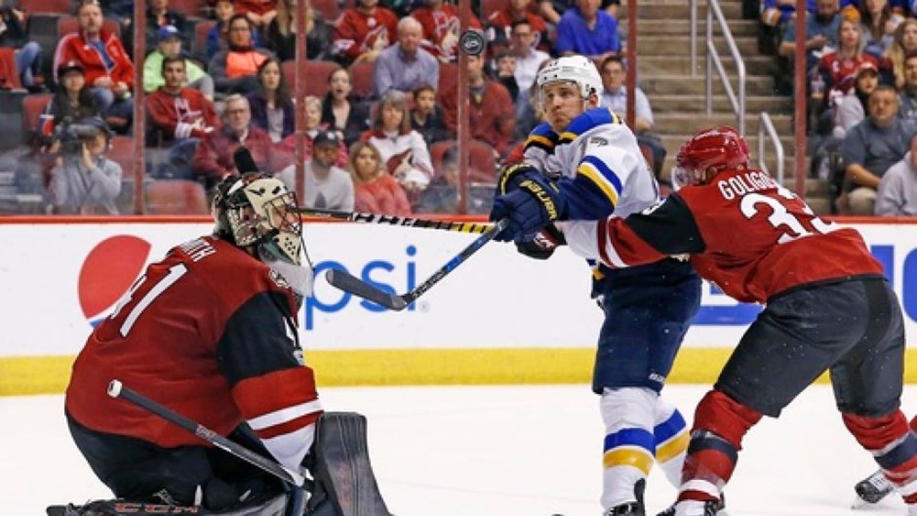 St. Louis Blues left wing Jaden Schwartz, middle, tries to hit the puck in the air as Alex Goligoski, right, defends and goalie Mike Smith, left, moves over to make a possible save during the second period of an NHL hockey game Saturday, March 18, 2017, in Glendale, Ariz. (AP Photo/Ross D. Franklin)
