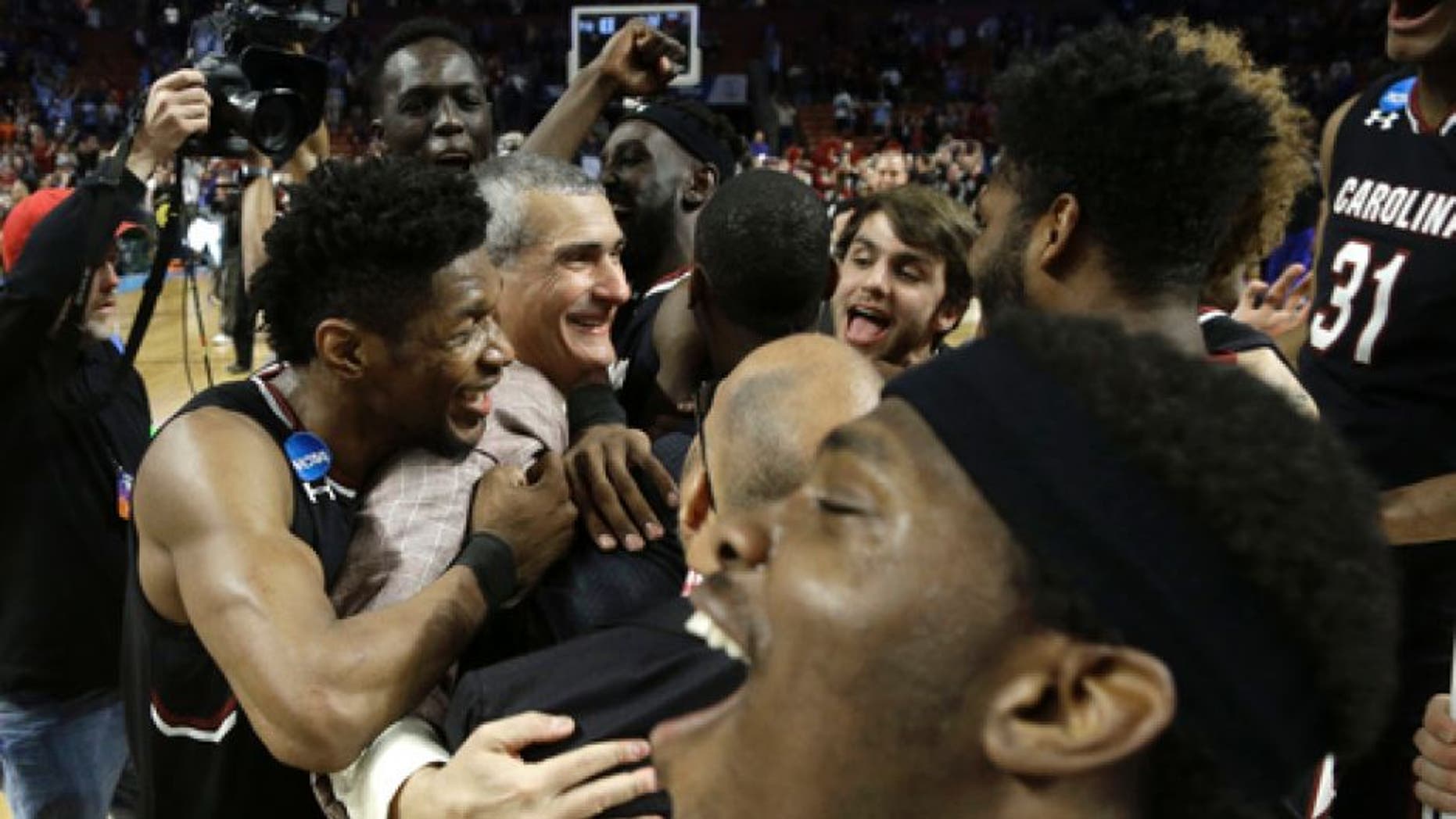 South Carolina head coach Frank Martin, second from left, is hugged by Chris Silva, left, as they celebrate after a second-round game against Duke in the NCAA men's college basketball tournament in Greenville, S.C., Sunday, March 19, 2017. (AP Photo/Chuck Burton)