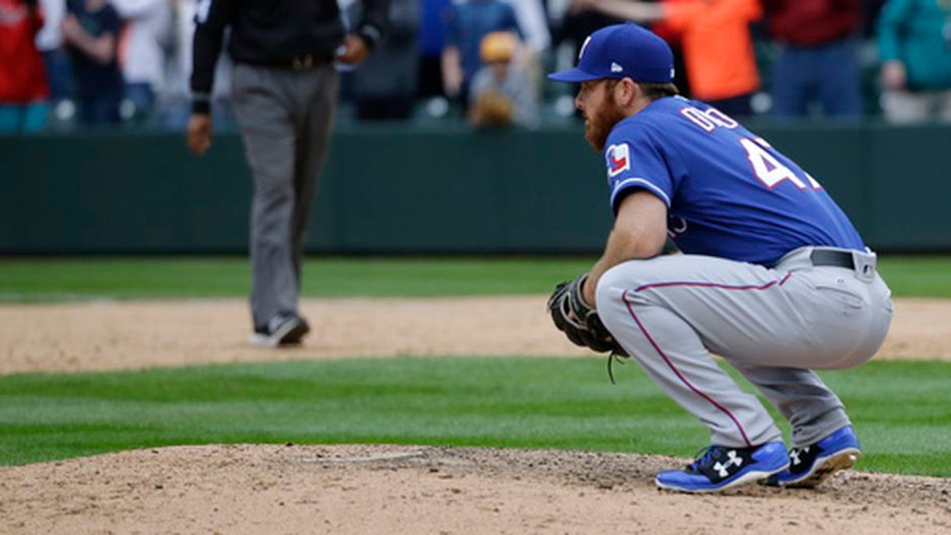 Texas Rangers closing pitcher Sam Dyson crouches on the mound after he gave up a walk-off RBI single to Seattle Mariners' Nelson Cruz in the ninth inning of a baseball game, Sunday, April 16, 2017, in Seattle. The Mariners won, 8-7. (AP Photo/Ted S. Warren)