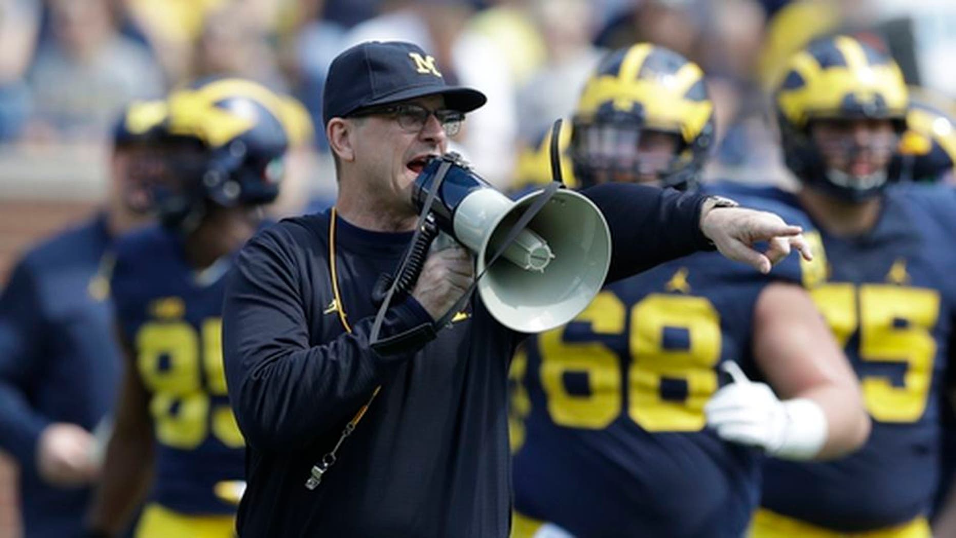 FILE - In this April 15, 2017, file photo, Michigan head coach Jim Harbaugh talks to his players during the NCAA college football team's spring game, in Ann Arbor, Mich. The increasing visibility of spring football games has offered plenty of feel-good moments and fan-friendly opportunities. What they don't provide is much insight into what these teams will be doing this fall. With so many spring games on television, teams don't want to give anything away to rival coaches who may be tuning in. (AP Photo/Carlos Osorio, File)