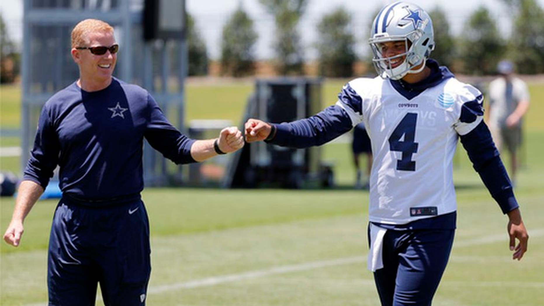 Dallas Cowboys head coach Jason Garrett, left, gets quarterback Dak Prescott (4) a fist bump as the two walk off the field after an NFL football organized team activities practice at the team's training facility, Wednesday, May 24, 2017, in Frisco, Texas. (AP Photo/Tony Gutierrez)