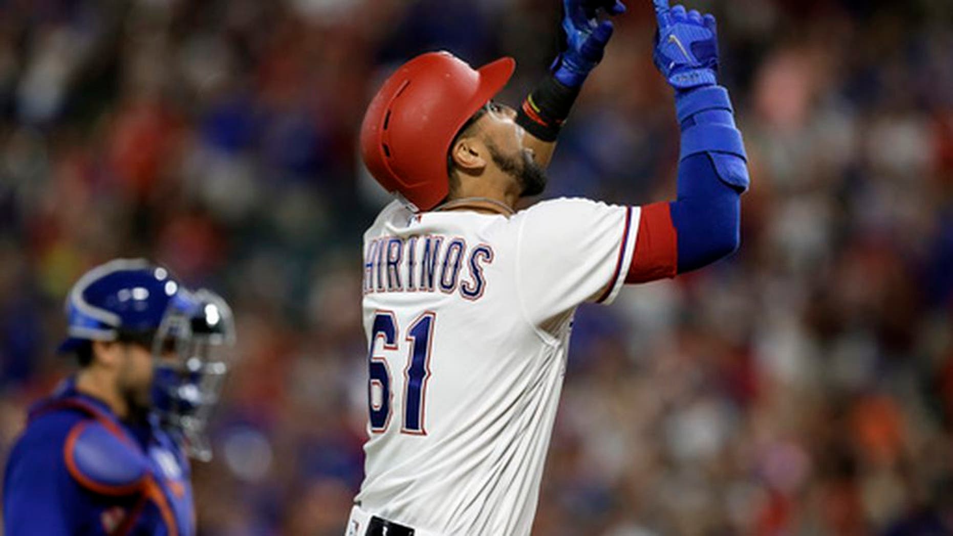 Texas Rangers' Robinson Chirinos (61) points skyward, celebrating his two-run home run, as New York Mets catcher Travis d'Arnaud walks back to the plate during the eighth inning of a baseball game, Wednesday, June 7, 2017, in Arlington, Texas. (AP Photo/Tony Gutierrez)