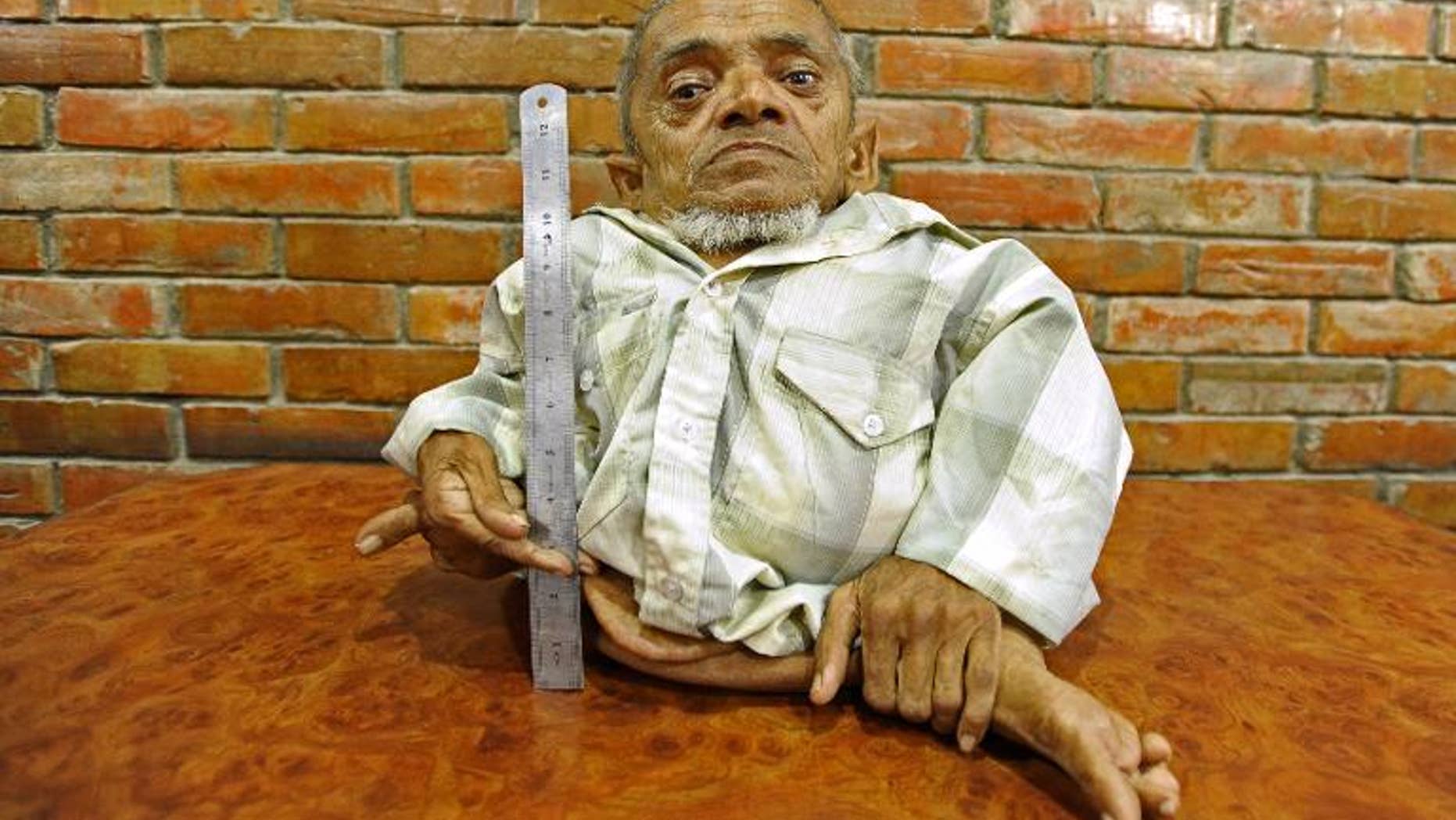In this photograph taken on September 17, 2013, Master Nau, a 73-year-old Nepali, poses for a photo next to a ruler in Kathmandu