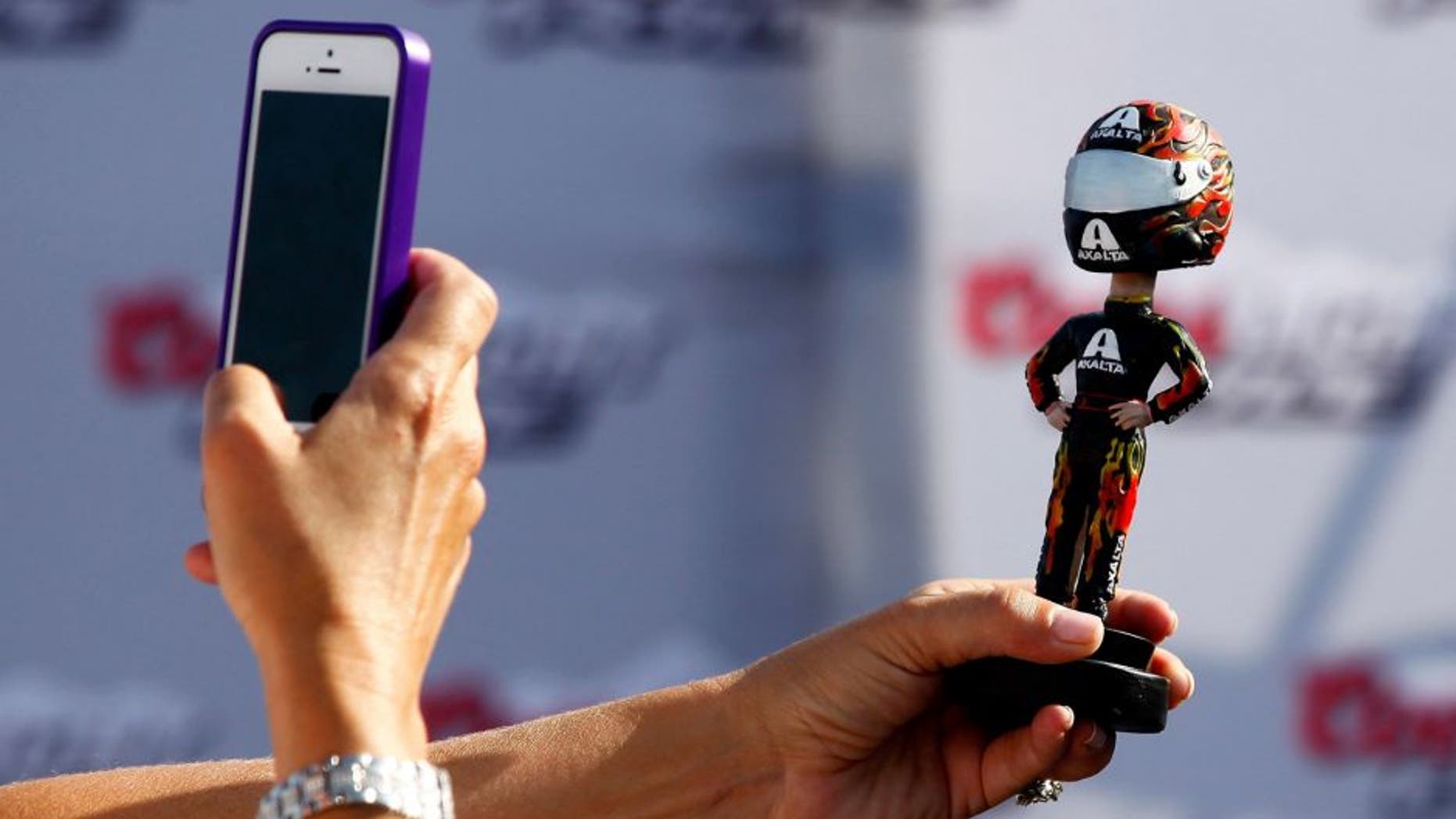 BROOKLYN, MI - AUGUST 16: A fan takes a picture of a bobblehead during practice for the NASCAR Sprint Cup Series Pure Michigan 400 at Michigan International Speedway on August 16, 2014 in Brooklyn, Michigan. (Photo by Brian Lawdermilk/NASCAR via Getty Images)