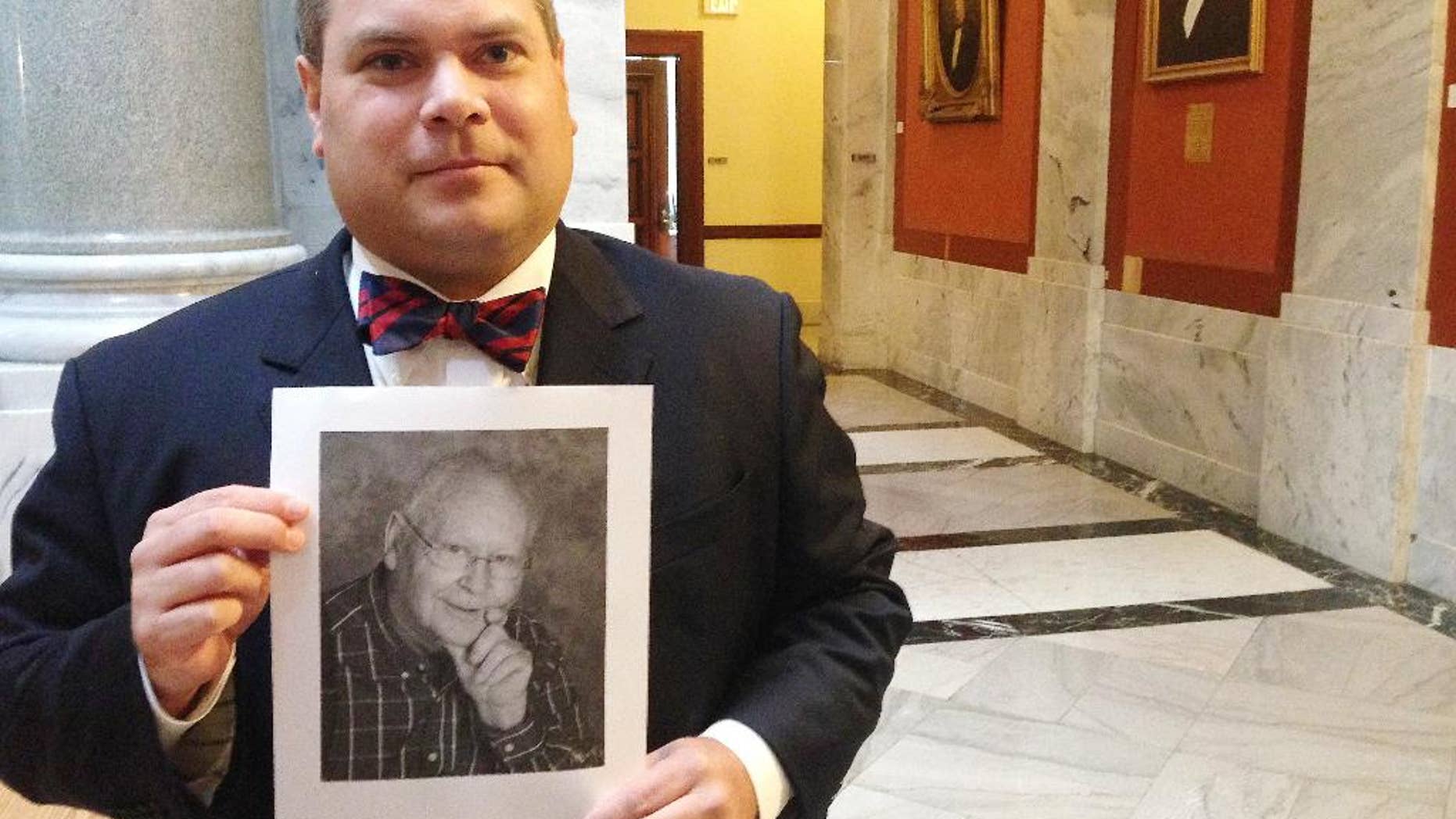 Attorney Steven Megerle holds a photo of his client, Elmer Riehle, outside of the Kentucky Supreme Court on Friday, Aug. 19, 2016, in Lexington, Ky. A jury declared Riehle mentally incompetent in 2008 and appointed his wife as his legal guardian. Now, Riehle wants a divorce. But Kentucky law won't allow it. The state Supreme Court will decide. (AP Photo/Adam Beam)