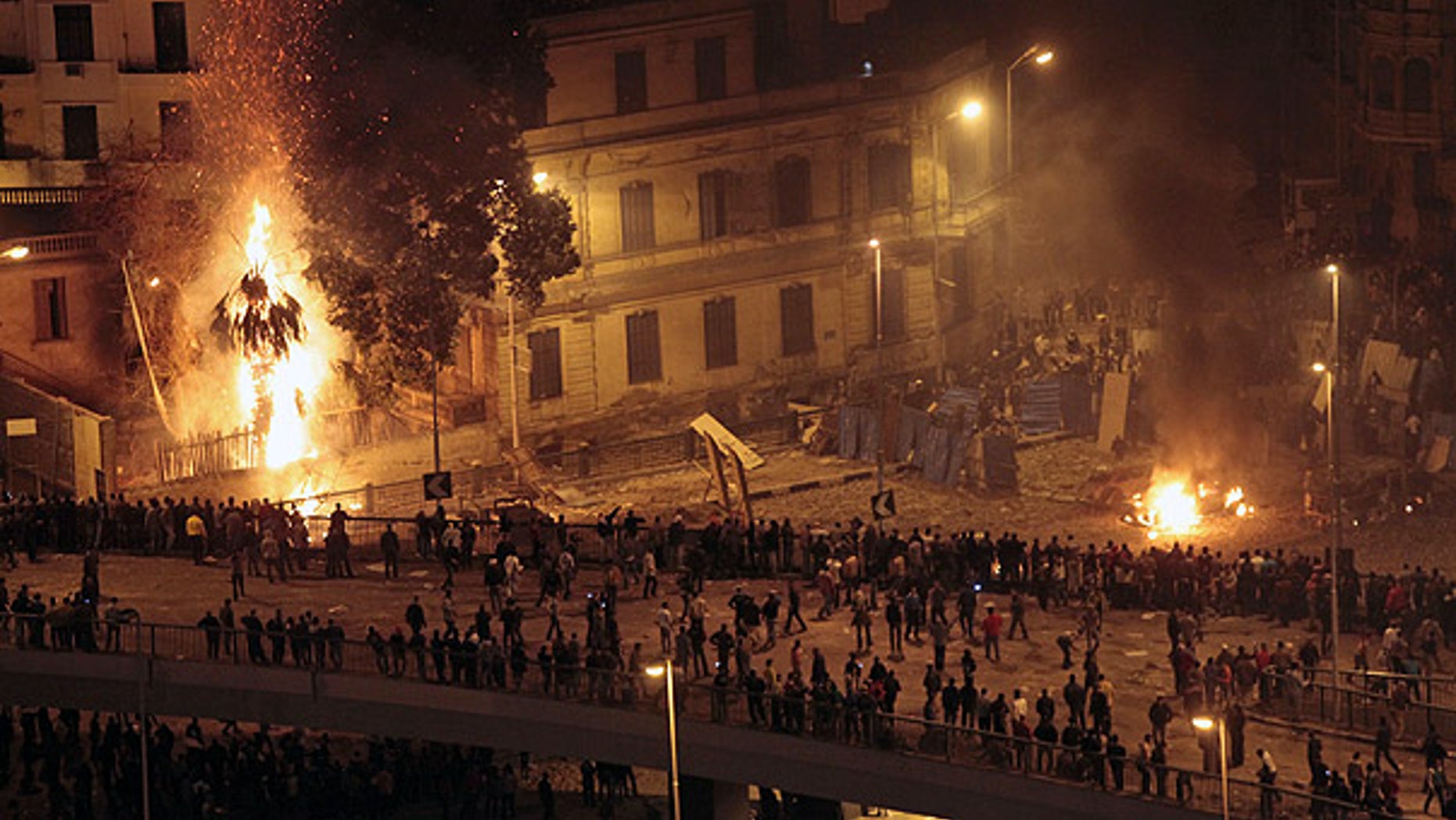 Feb. 3: Pro-Mubarak demonstrators, bottom, clash with anti-government demonstrators, top right, as a palm tree burns from a firebomb, in Tahrir Square, Cairo.