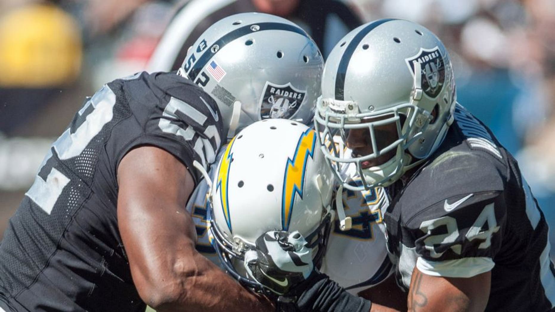 Oct 12, 2014; Oakland, CA, USA; San Diego Chargers running back Branden Oliver (43) rushes for a gain against Oakland Raiders outside linebacker Khalil Mack (52) and free safety Charles Woodson (24) during the second quarter at O.co Coliseum. Mandatory Credit: Ed Szczepanski-USA TODAY Sports