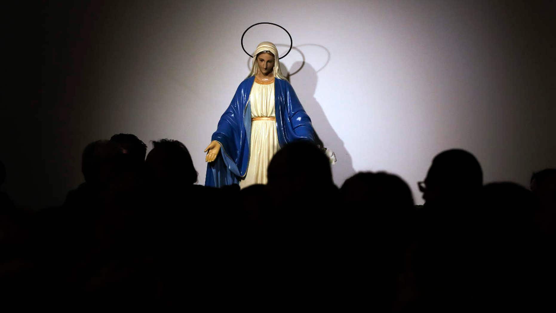 A statue of the Virgin Mary is seen in background as faithful attend a Mass celebrated by Pope Francis at the St. Mary of Setteville di Guidonia parish church, in the outskirts of Rome, Sunday, Jan. 15, 2017.