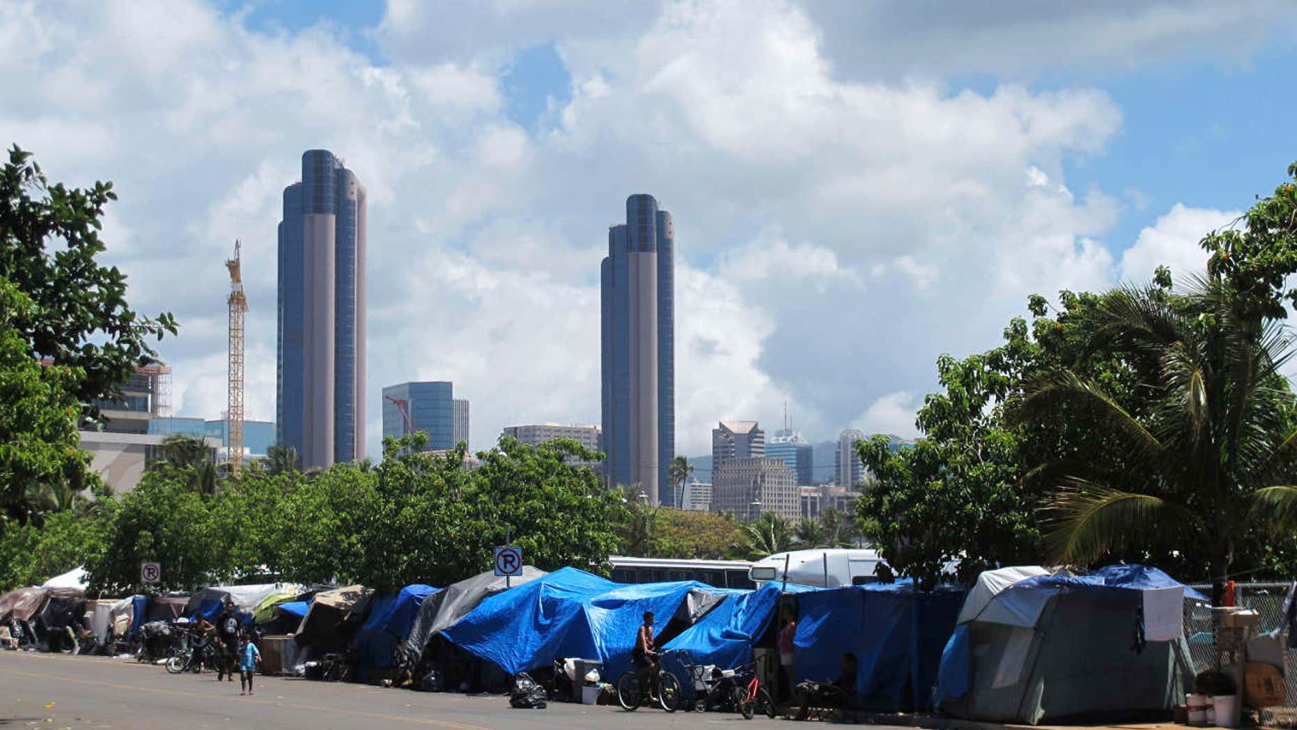 FILE - In this June 30, 2015, file photo, people camp out on a sidewalk in the Kakaako neighborhood of Honolulu, Hawaii.
