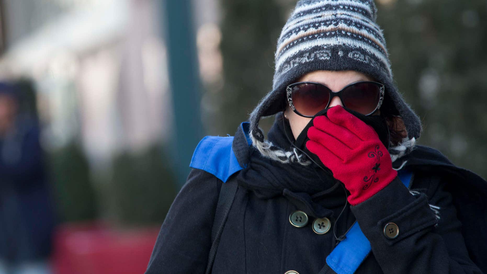 A woman lifts her scarf up in front of her nose to shield from the cold air, Friday, Feb. 12, 2016, in New York.
