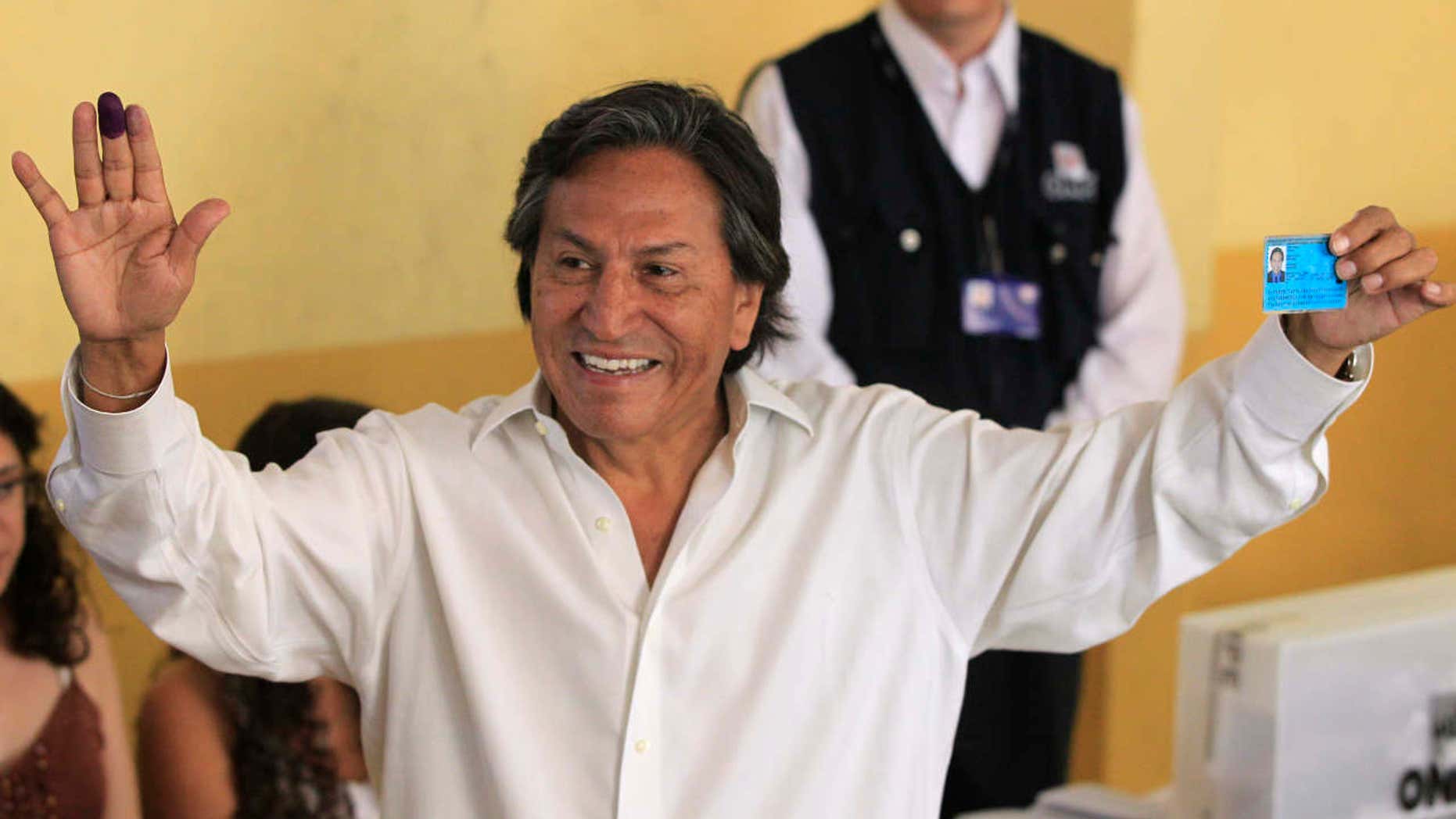 FILE -- In this April 10, 2011 file photo, then presidential candidate Alejandro Toledo holds up his ink-stained finger and identification card after voting in the general elections, in Lima, Peru.