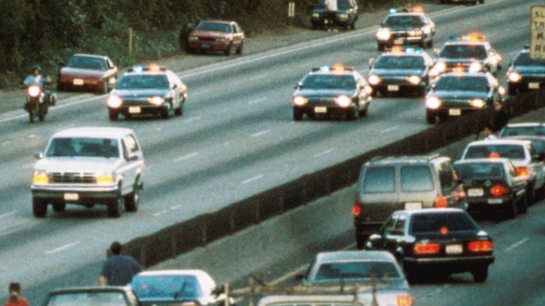 LOS ANGELES - JUNE 17: Motorists stop and wave as police cars pursue the Ford Bronco (white, R) driven by Al Cowlings, carrying fugitive murder suspect O.J. Simpson, on a 90-minute slow-speed car chase June 17, 1994 on the 405 freeway in Los Angeles, California. Simpson's friend Cowlings eventually drove Simpson home, with Simpson ducked under the back passenger seat, to Brentwood where he surrendered after a stand-off with police. (Photo by Jean-Marc Giboux/Liaison)
