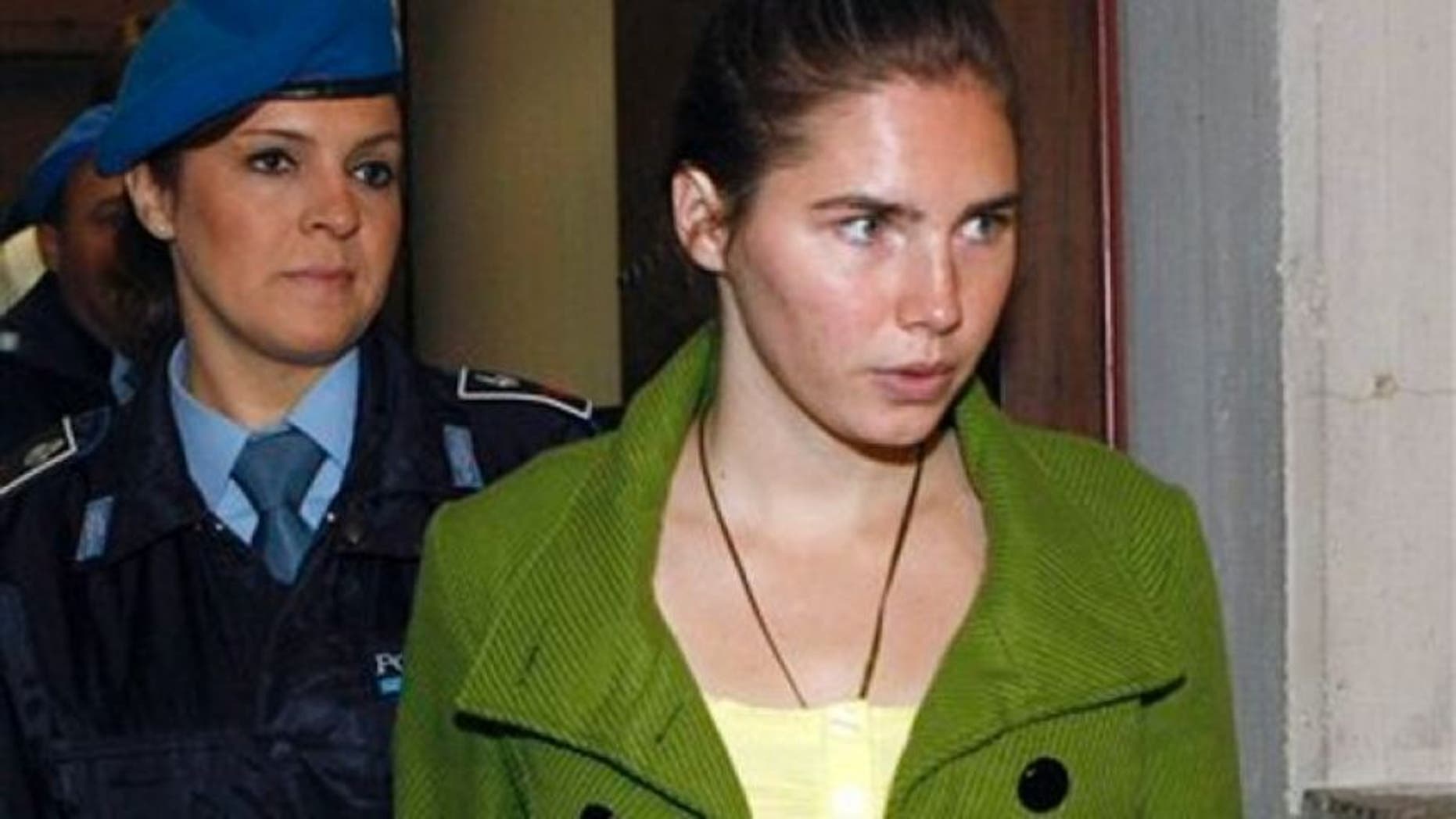 Dec. 4, 2009: Amanda Knox is accompanied by a penitentiary police officer prior to a final hearing at the court in Perugia, Italy. Knox was found guilty of murdering her British roommate Meredith Kercher.