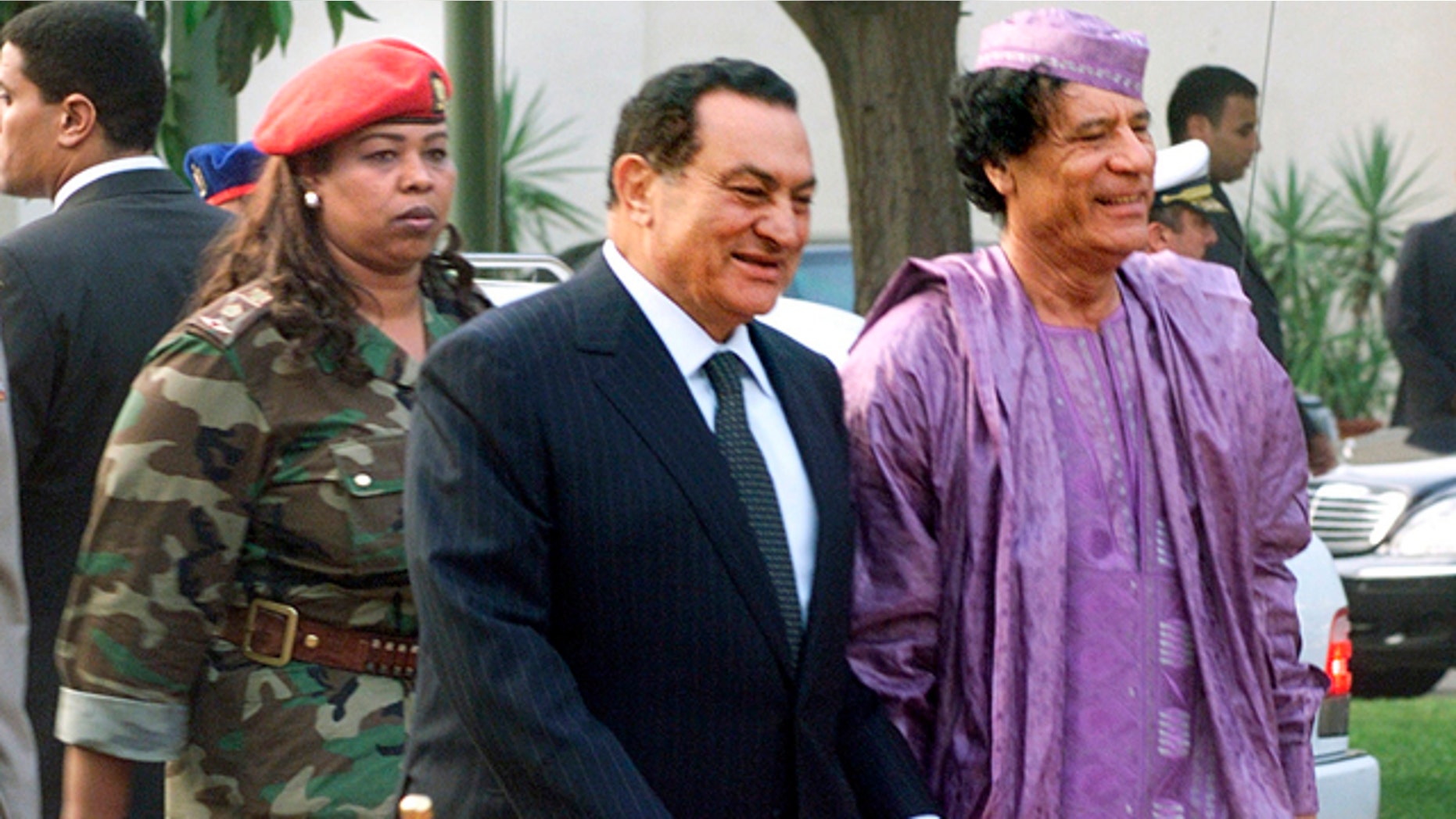 This July 21, 2002, file photo shows Egyptian President Hosni Mubarak, center, welcoming Libyan leader Moammar Gadhafi, right, who is guarded by a female bodyguard, left, upon his arrival at the Presidential Palace in Cairo.