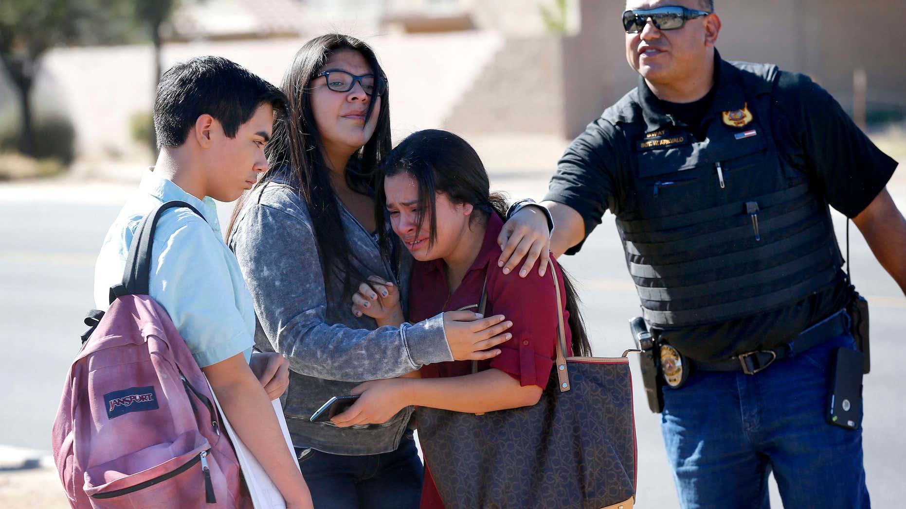 Students embrace after leaving campus, Friday, Feb. 12, 2016, in Glendale, Ariz.