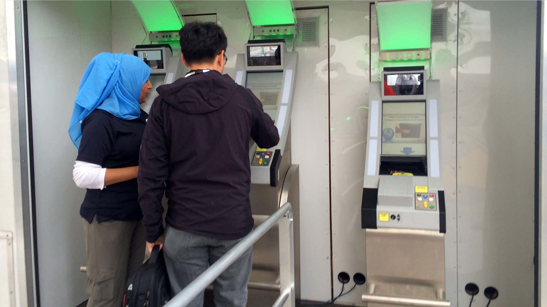Feb. 18, 2016: A Customs and Border protection officer helps a man from China scan his documents while a camera records his iris and facial features to verify his documents while leaving San Diego on his way to Mexico.