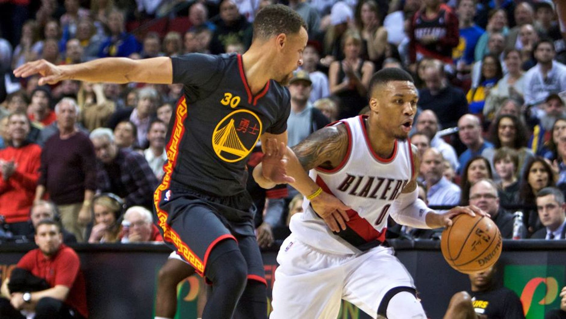 Portland Trail Blazers guard Damian Lillard moves the ball past Golden State Warriors guard Stephen Curry, left, during the second half of an NBA basketball game in Portland, Ore., Friday, Feb. 19, 2016. (AP Photo/Craig Mitchelldyer)