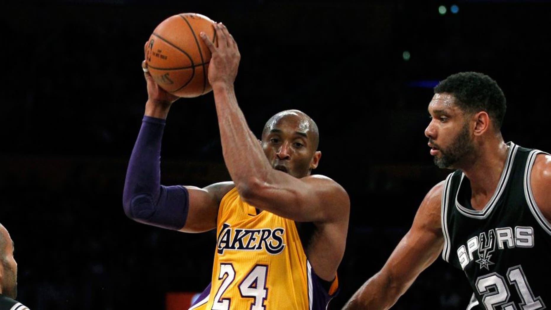 Los Angeles Lakers forward Kobe Bryant (24) drives the lane against San Antonio Spurs guard Tony Parker (9) and center Tim Duncan (21) during the first half of an NBA basketball game in Los Angeles, Friday, Feb. 19, 2016. (AP Photo/Alex Gallardo)