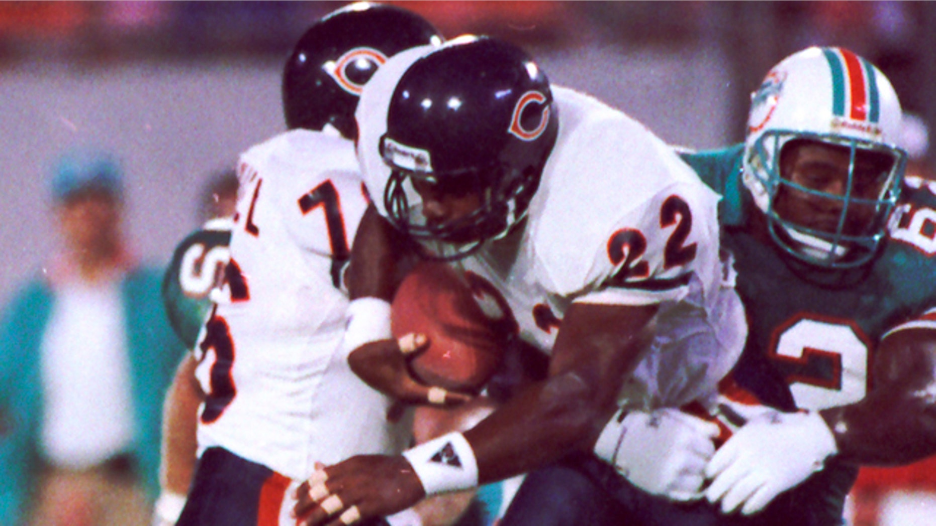 In this Aug. 14, 1989, file photo, Chicago Bears safety Dave Duerson (22) scrambles for running room after intercepting a pass as Miami Dolphins Jeff Uhlenhake (63) grabs hold during an NFL football game in Miami.
