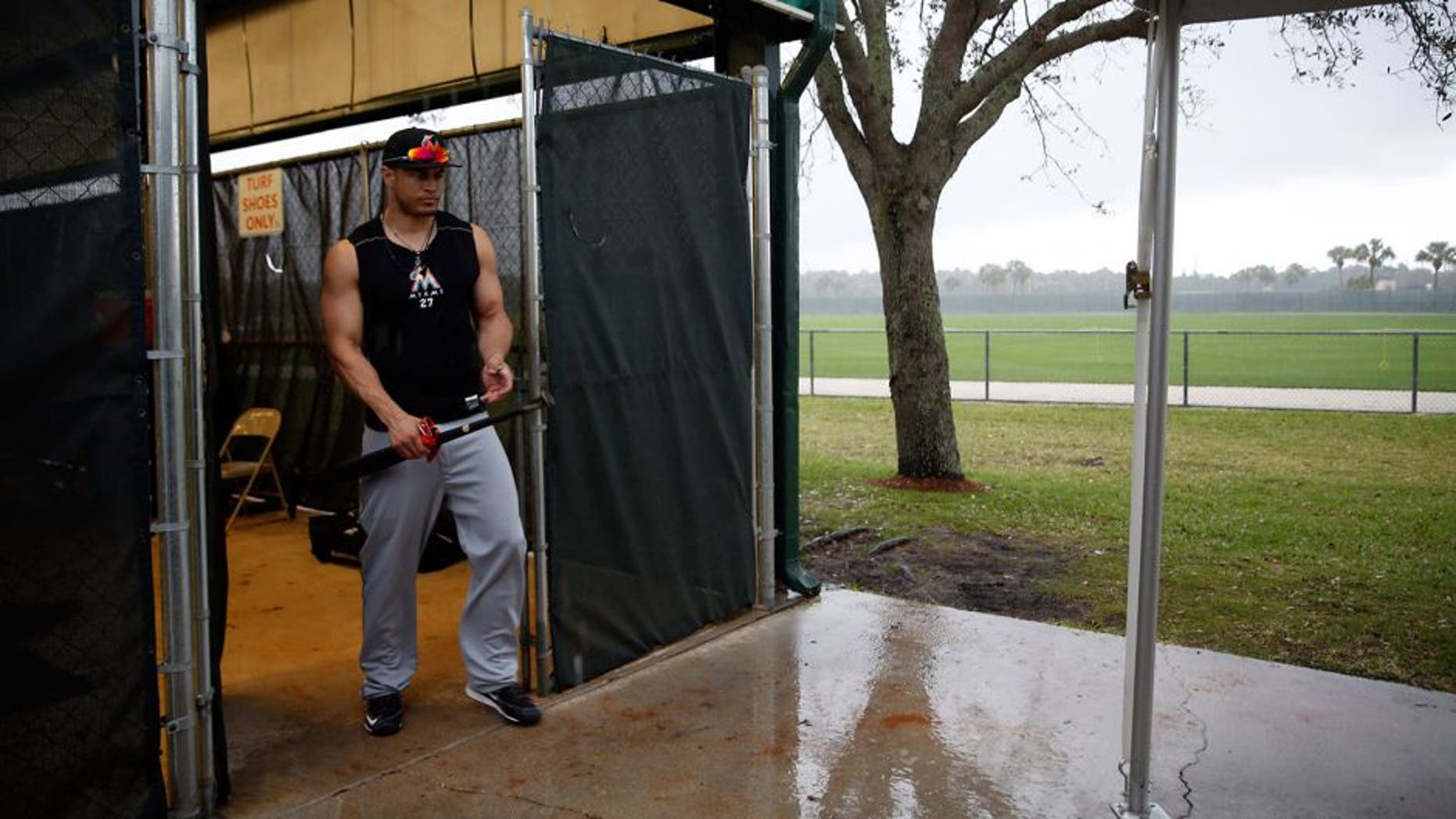 Miami Marlins' Giancarlo Stanton steps out of a batting cage as a steady rain falls during spring training baseball practice Tuesday, Feb. 23, 2016, in Jupiter, Fla. (AP Photo/Jeff Roberson)
