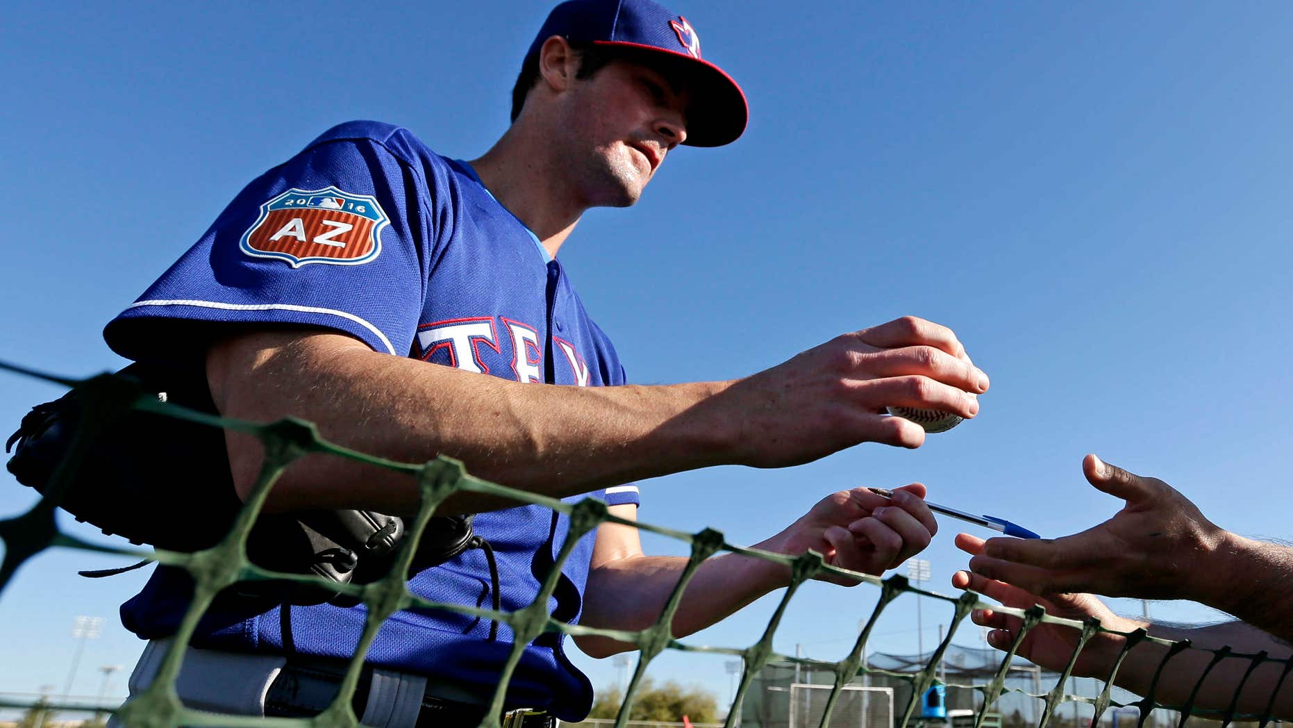 FILE - In this Feb. 21, 2016, file photo, Texas Rangers pitcher Cole Hamels signs autographs during spring training baseball practice, in Surprise, Ariz.