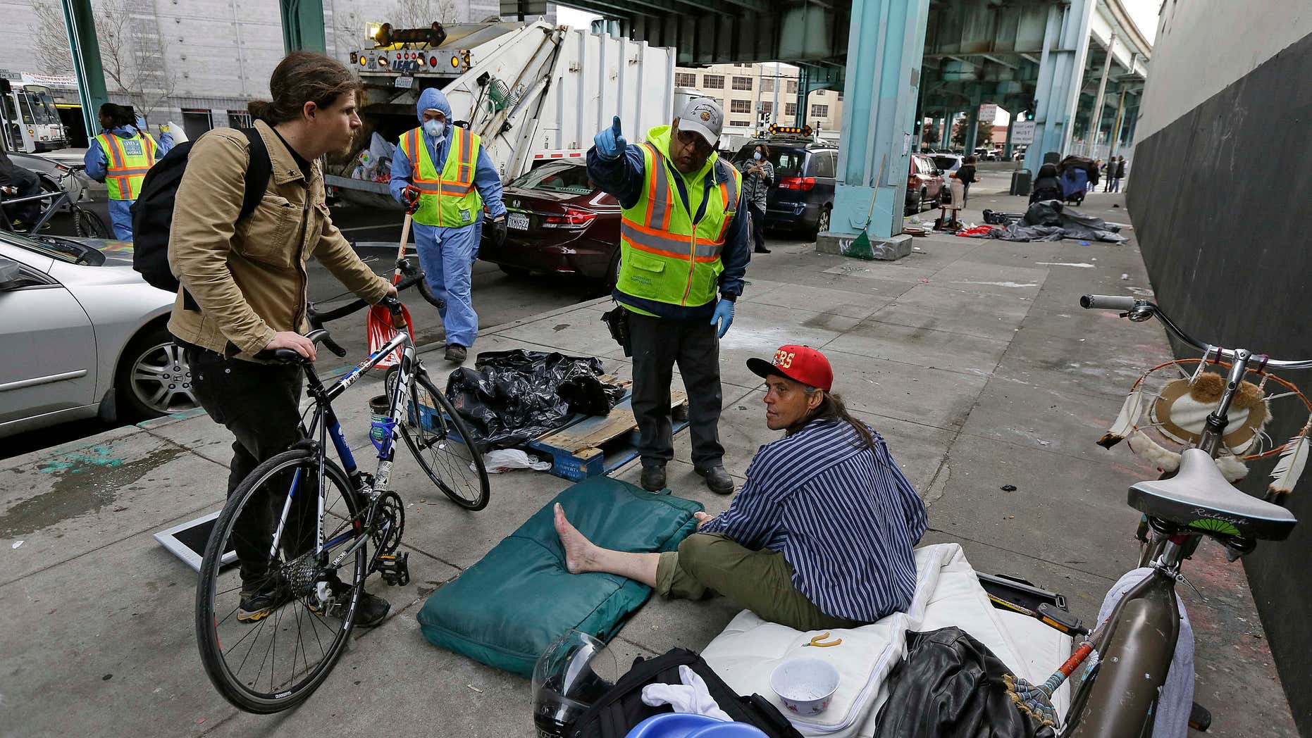 A city worker tells a homeless man that the area next to him on is about to be power washed and points to an area he might want to move Friday, Feb. 26, 2016, in San Francisco.