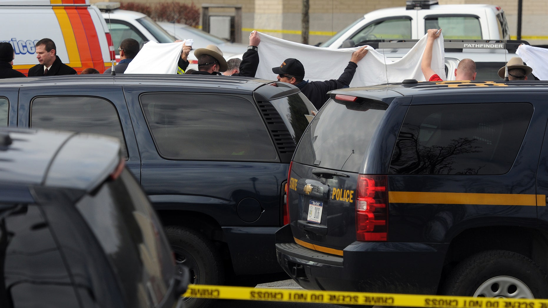 In this photo taken on Thursday, Nov. 21, 2013, State police investigate near a vehicle in a supermarket parking lot in Pleasant Valley, N,Y., where 49-year-old pharmacist Abbas Lodhi and one of sons were found shot dead. Police say they later found the body of the man's other son at the family's nearby home. Police are continuing to search for the man's 43-year-old wife Sarwat Lodhi, who is missing and has unspecified injuries. They describe her as a victim in the case. (AP Photo/The Journal, Darryl Bautista) NO SALES. MIDDLETOWN OUT, KINGSTON OUT.