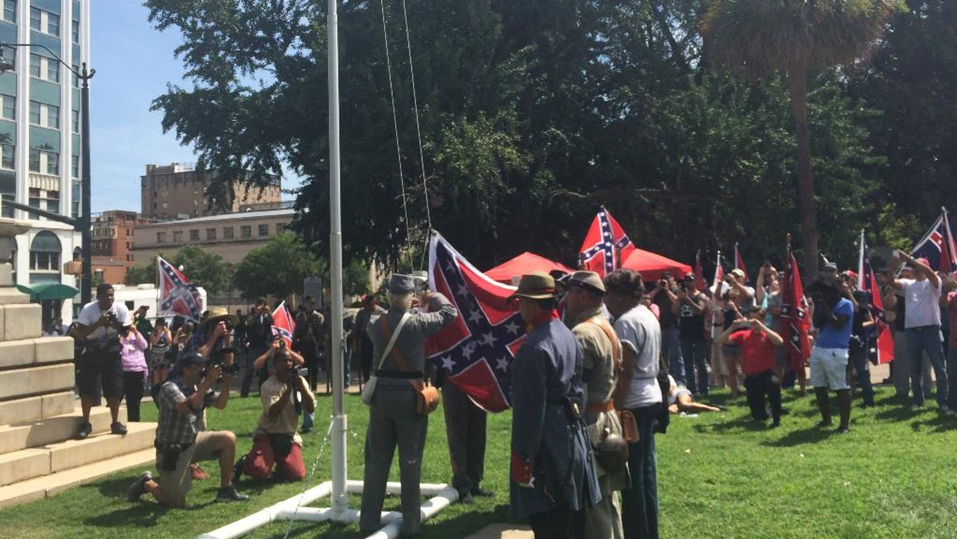 Supporters of the Confederate flag raise it on a temporary flagpole on the grounds of the Statehouse in Columbia, S.C., at a rally on Sunday, July 10, 2016. Counter-protesters showed up but the event was peaceful. (AP Photo/Meg Kinnard)