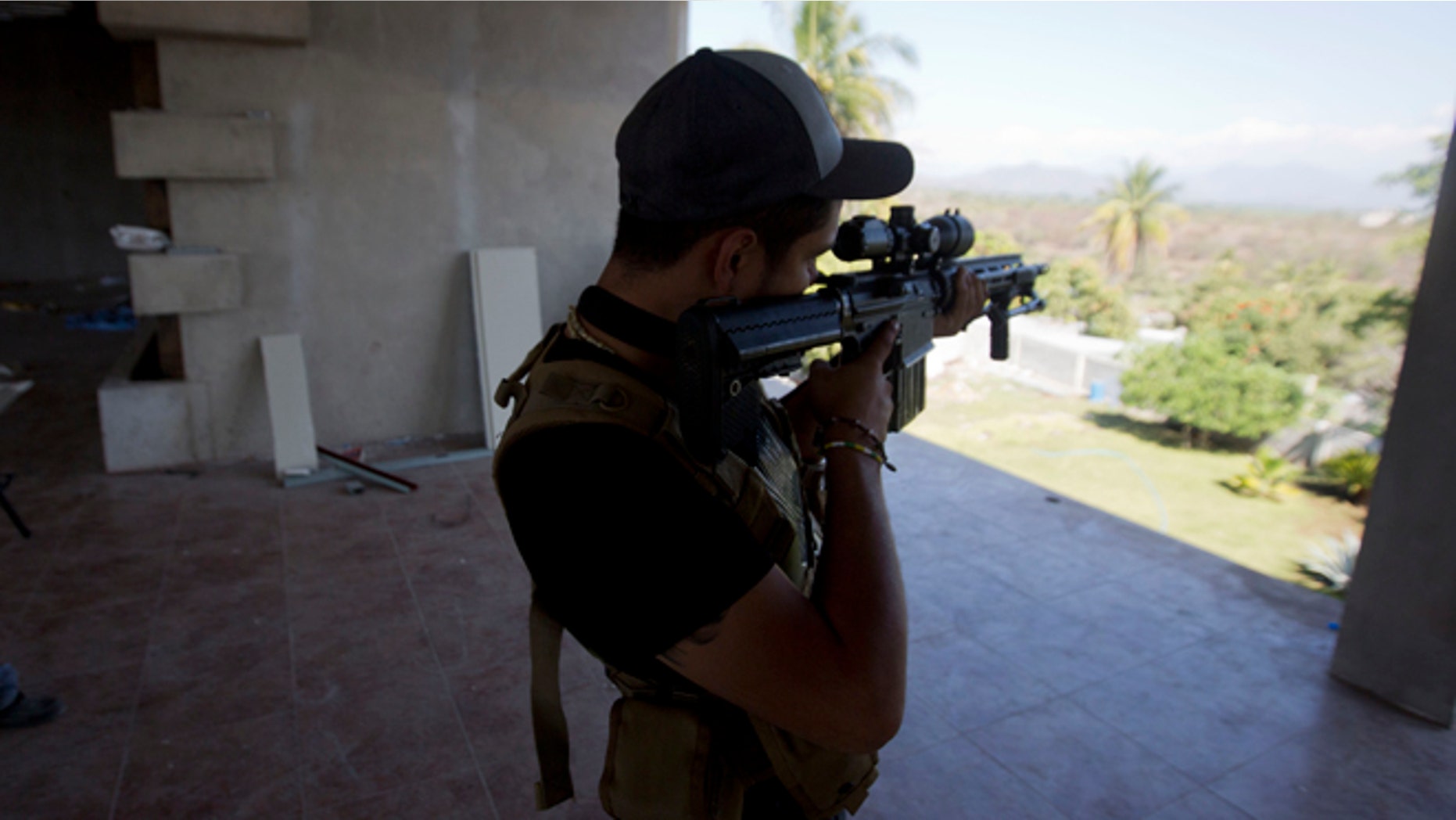 A man belonging to the Self-Defense Council of Michoacan, (CAM), peers through the sight of his weapon at a checkpoint in Nueva Italia, Mexico, Monday, Jan. 13, 2014. A day earlier the self-defenses encountered resistance as they tried to rid the town of the Knights Templar drug cartel while the government announced today that federal forces will take over security in a large swath of a western Mexico that has been hard hit by violence. (AP Photo/Eduardo Verdugo)
