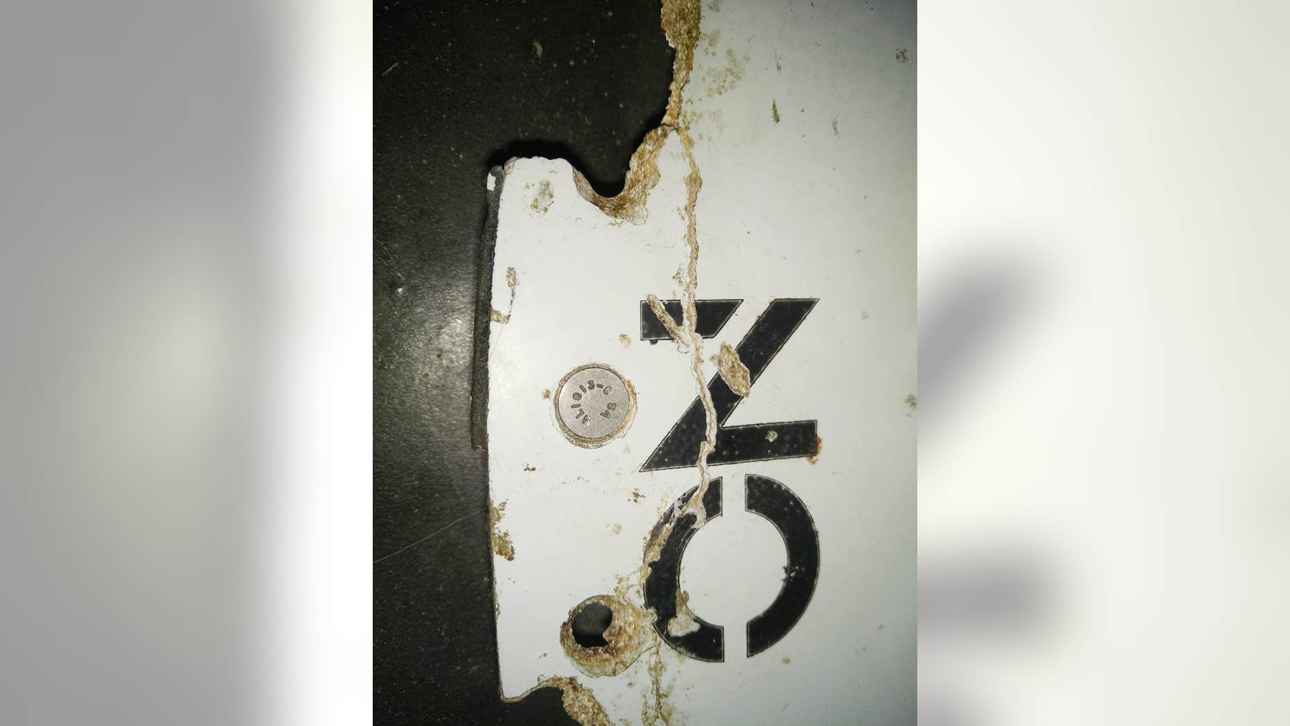 In this Feb. 28, 2016 image provided by Blaine Gibson and the Australian Transport Safety Bureau (ATSB), a piece of aircraft debris with the words "NO STEP" is photographed after it was found washed up on a beach in Mozambique.