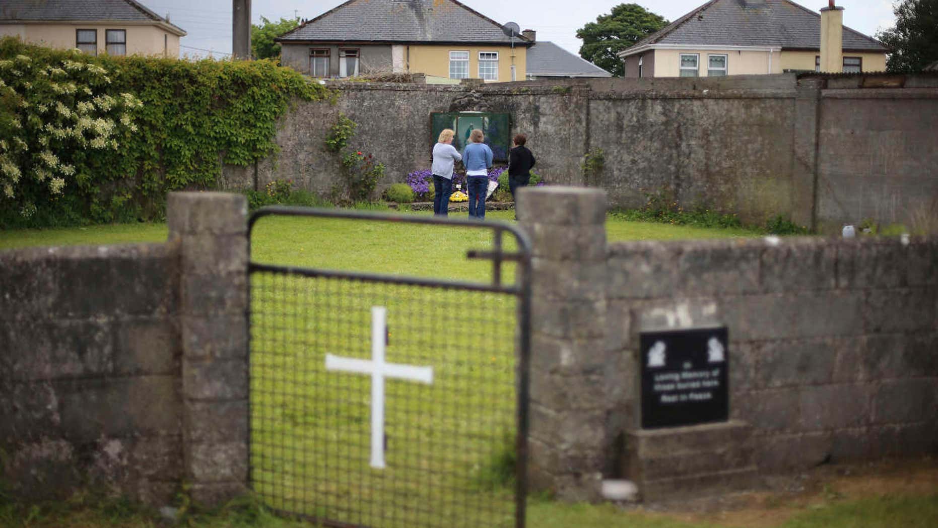 FILE In this June 7, 2014 file photo members of the public at the site of a mass grave for children who died in the Tuam mother and baby home, in Tuam, County Galway.