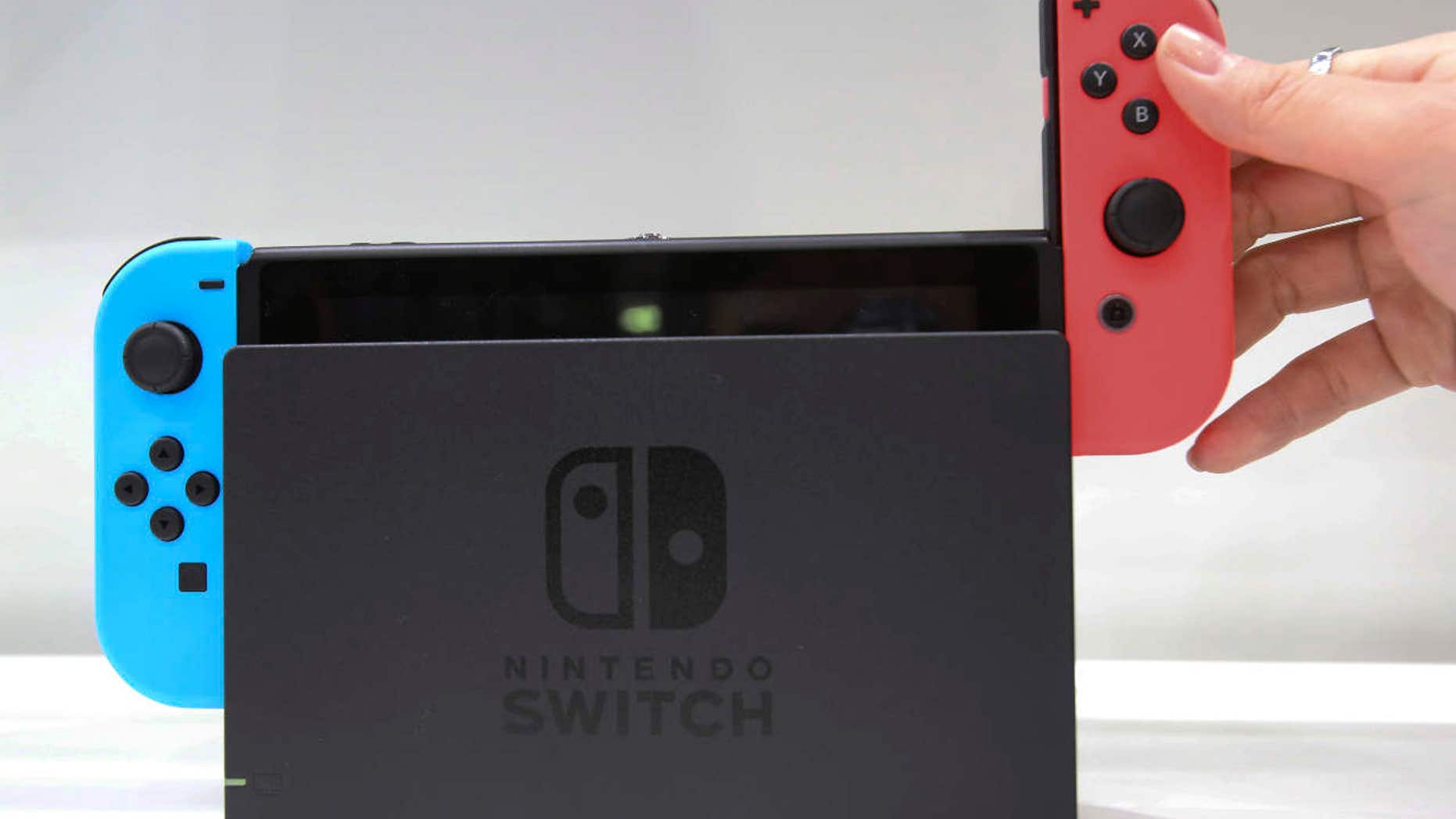 FILE - In this Friday, Jan. 13, 2017, file photo, a model puts the controller onto the Nintendo Switch during a presentation event of the new Nintendo Switch in Tokyo.